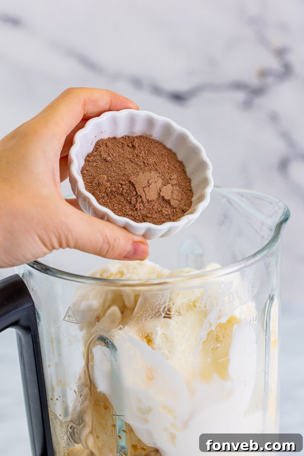 Adding hot chocolate mix into the blender with ice cream for the festive milkshake.