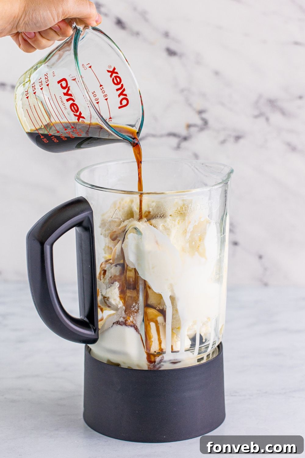Chocolate liquor being poured into the blender, adding a boozy depth to the milkshake mixture.