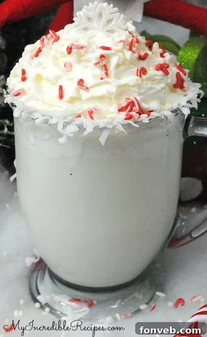 A cozy mug of creamy white hot chocolate with whipped cream, sprinkles, and a candy cane, perfect for holiday celebrations