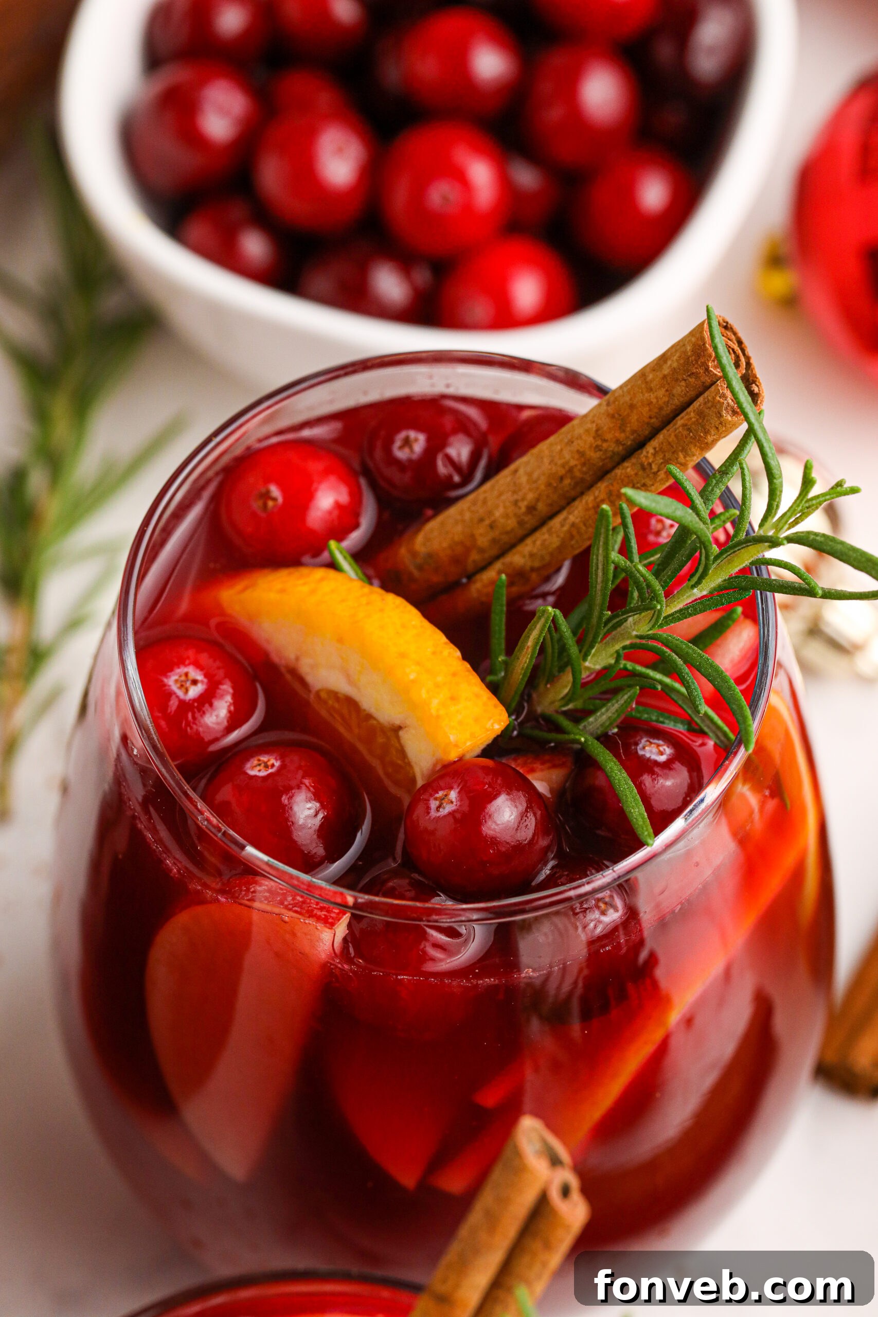 Cranberry Apple Christmas Sangria in a clear glass, garnished with fresh cranberries, apple slices, and cinnamon sticks.
