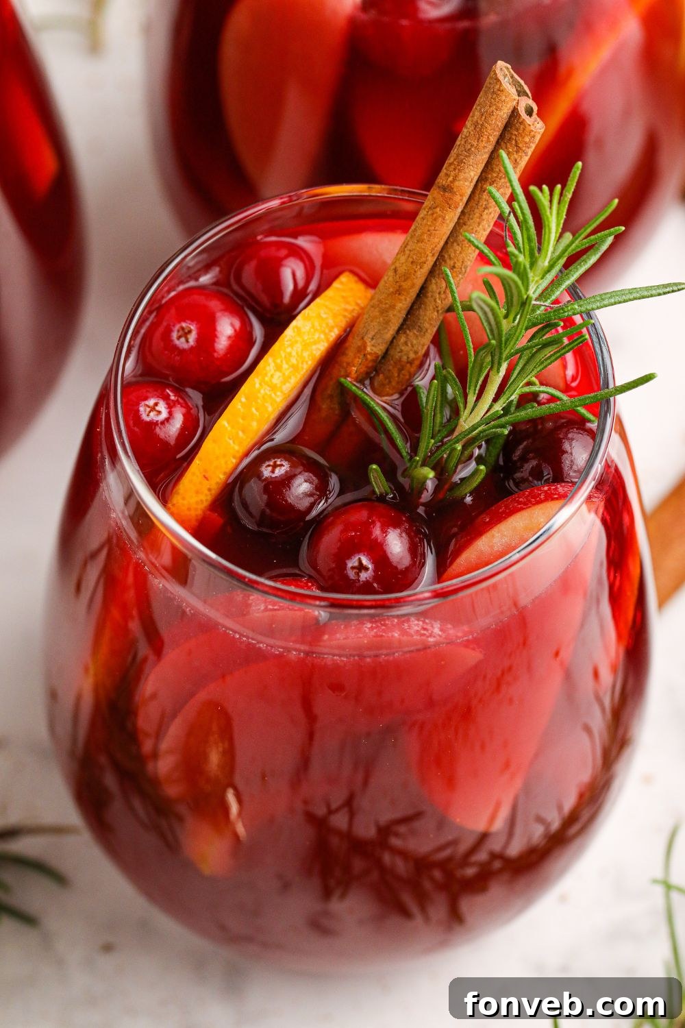 Glasses of wine cocktails with cranberries and orange slices, set for a festive occasion.