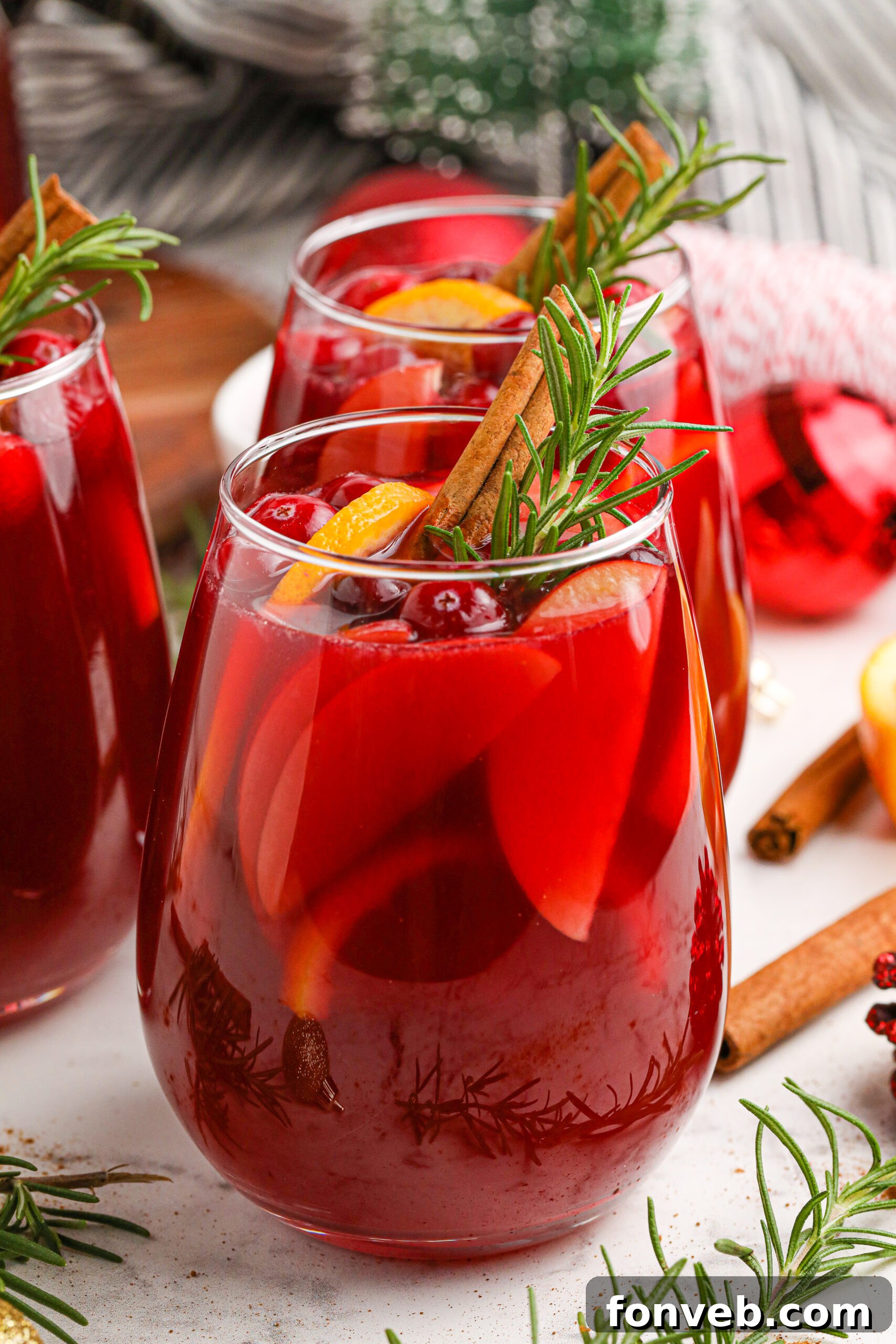 Cranberry Apple Christmas Sangria in a clear glass with fresh cranberries, apple slices, and cinnamon sticks.