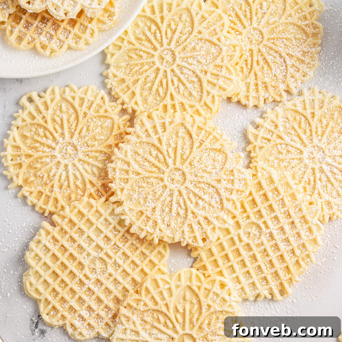 Pizzelles on marble table sprinkled with powdered sugar