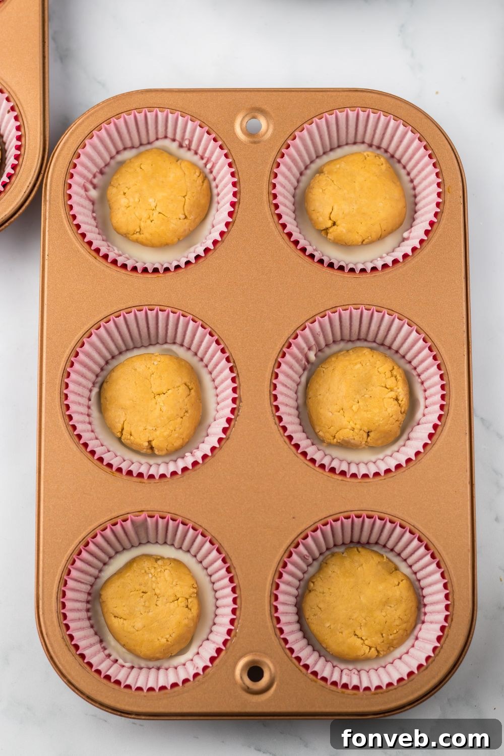 balls of peanut butter on top of chocolate in a muffin tin 