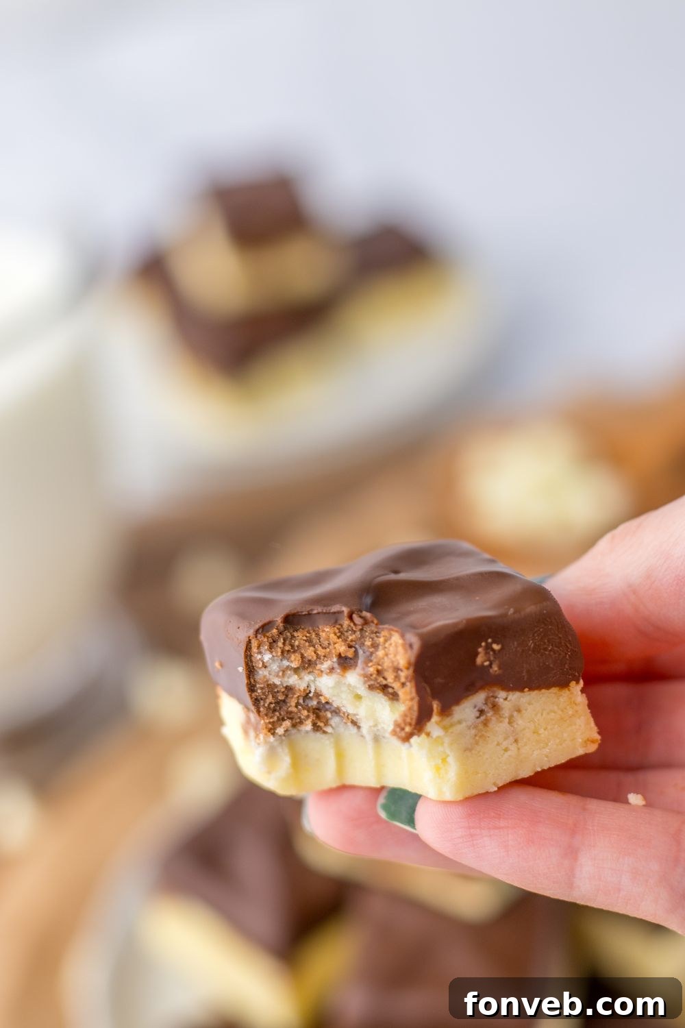 Boston Cream Dream Fudge 10 holding a piece of fudge with bite taken out