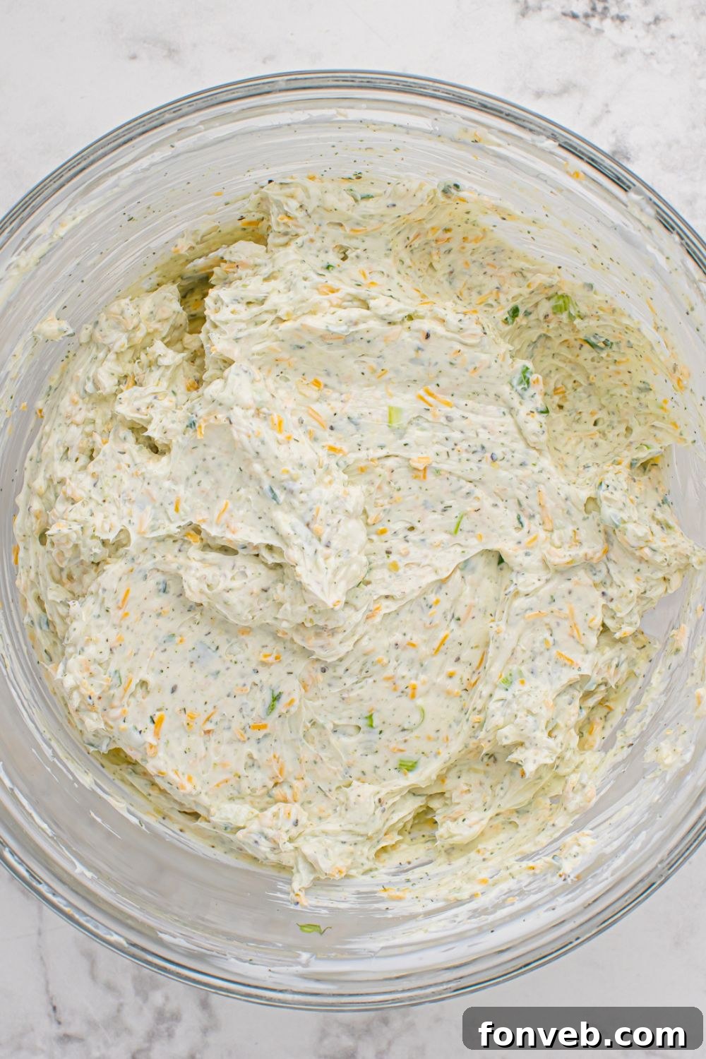 Cheese ball mixture being prepared in a mixing bowl on a kitchen table