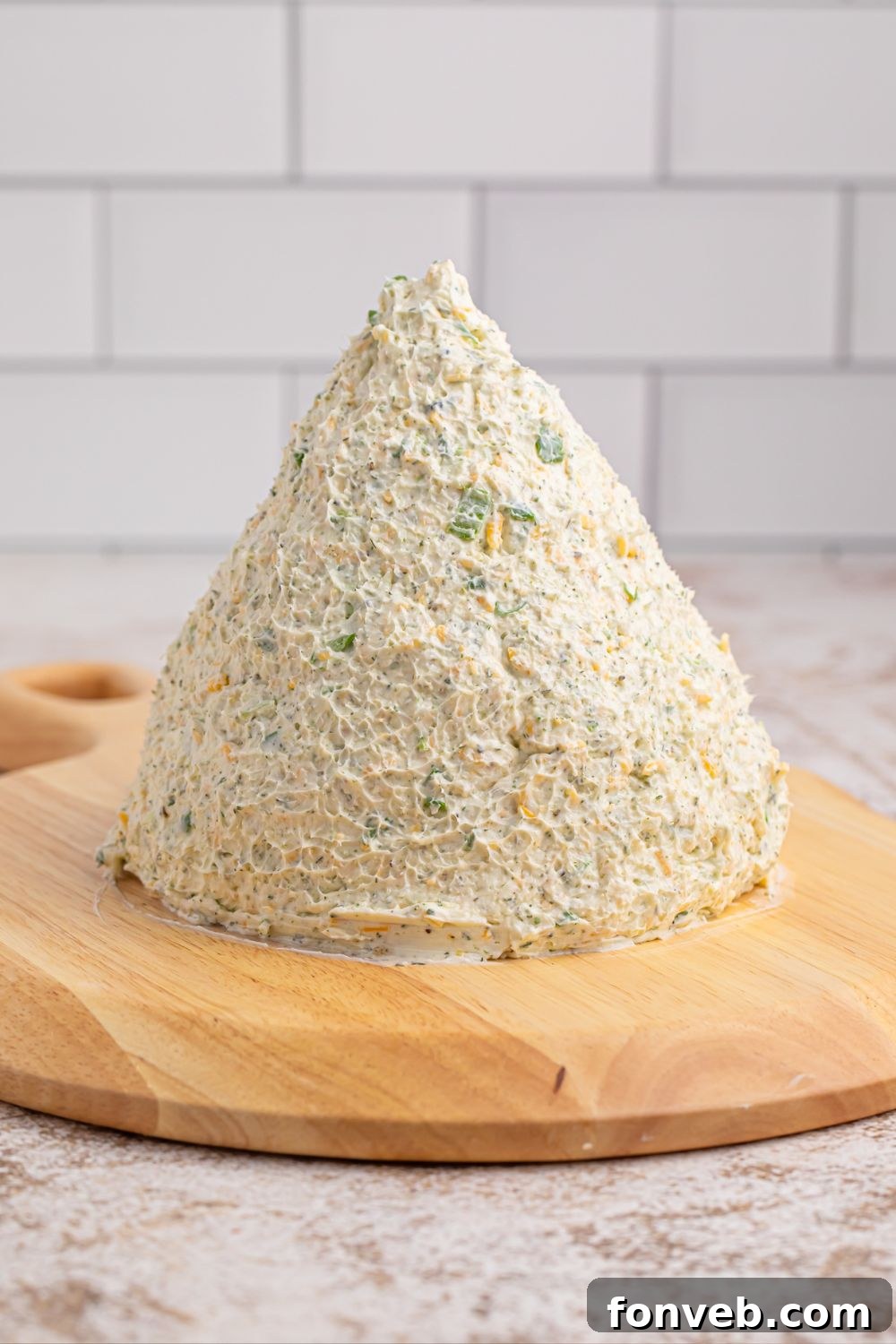 Dome shaped cheeseball placed on a wooden cutting board, ready for decorating