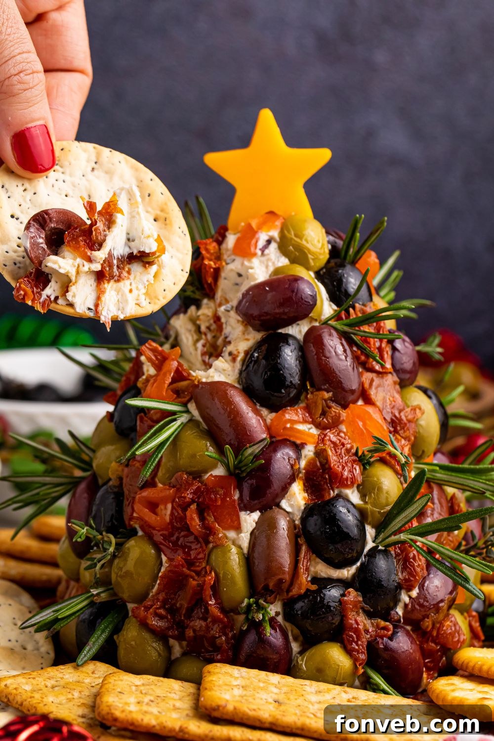 Cracker with cheeseball and some olives, illustrating serving