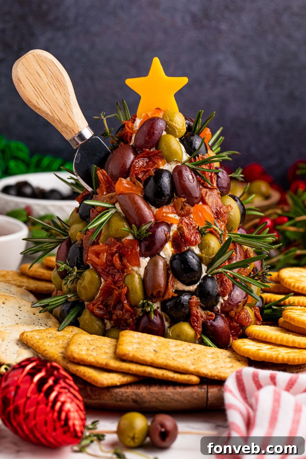 Antipasto Christmas Tree Cheeseball with a knife stuck in side of it, ready to be served at a party