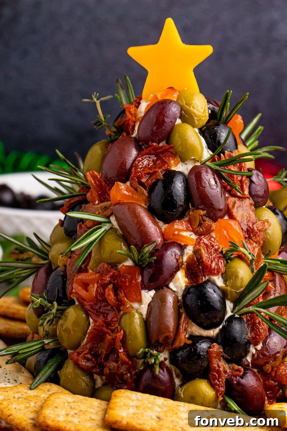 Cheese dip shaped like a tree with crackers around it on table, showing a festive serving option
