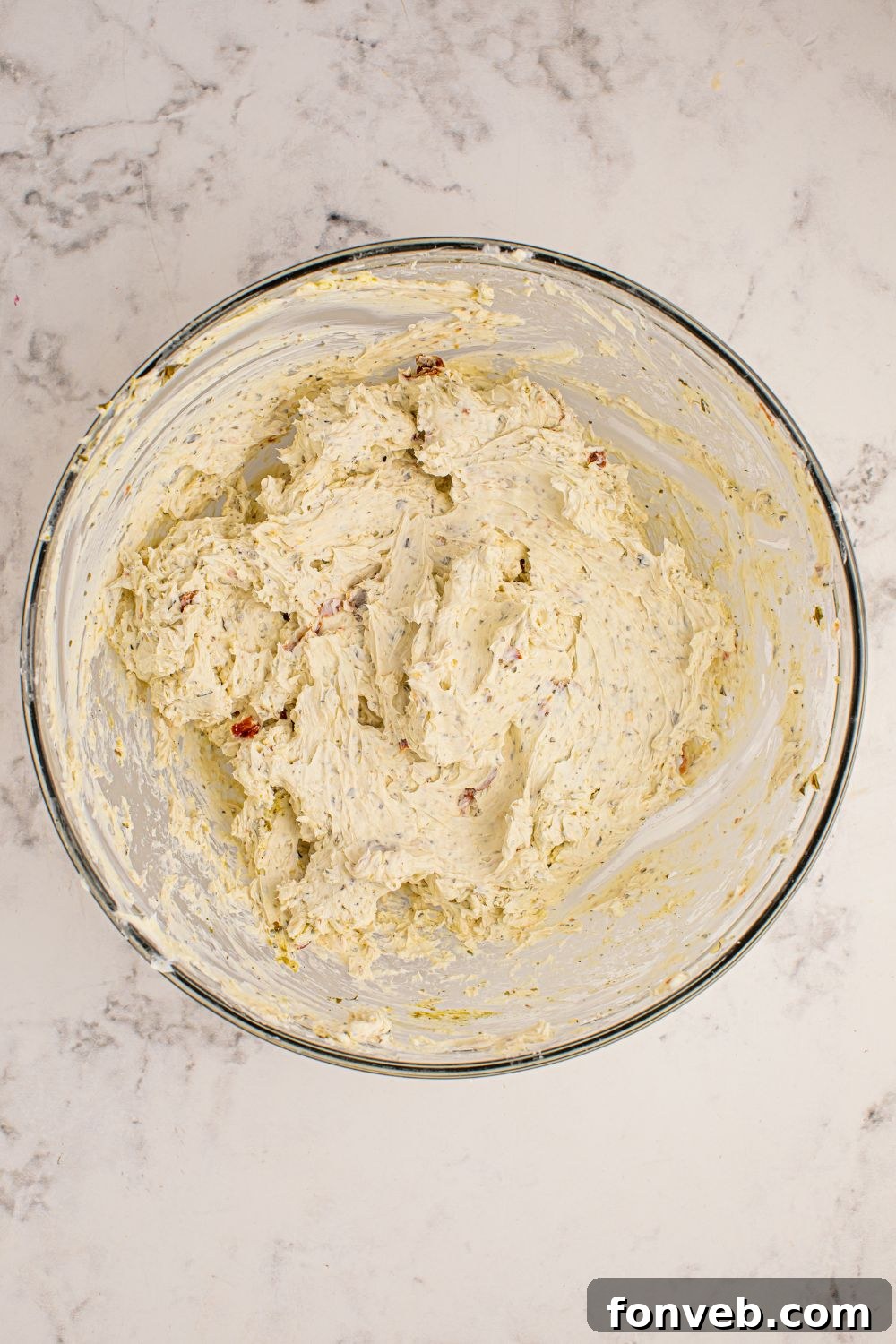 Cheeseball mixture in a clear glass bowl on a table, ready to be shaped