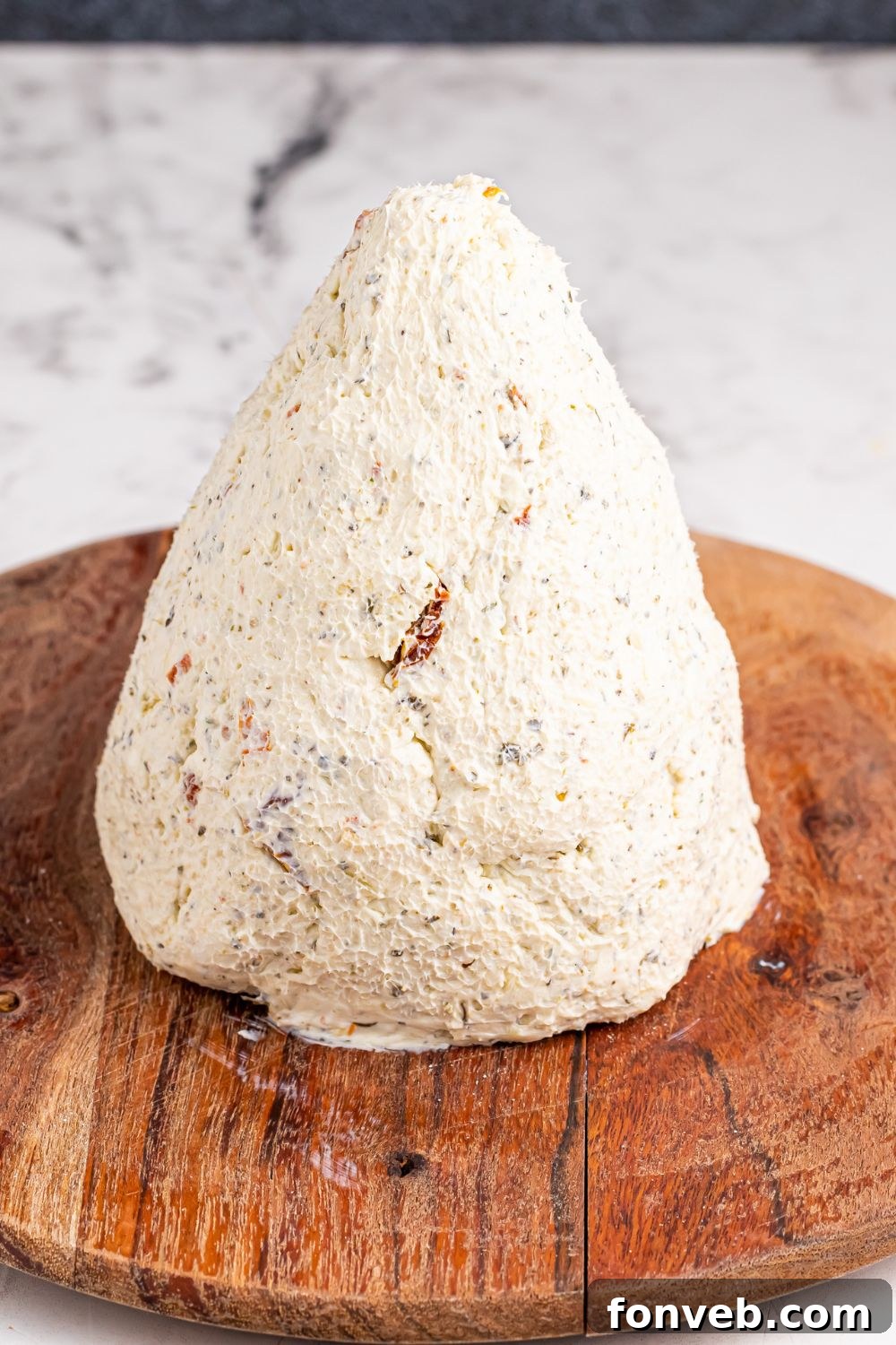 Cone shaped cheeseball on a round cutting board, forming the tree base
