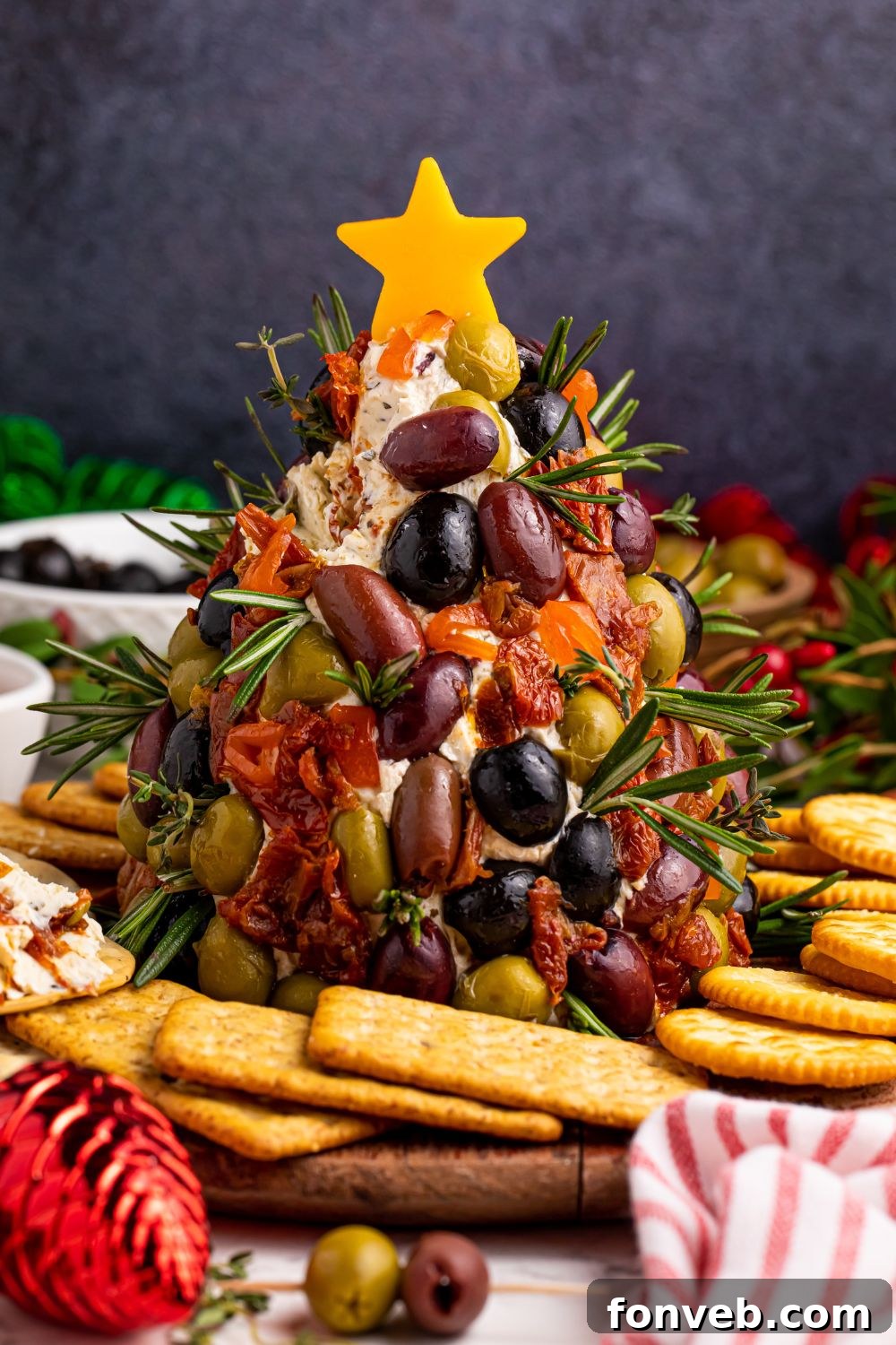 Decorated cheeseball on a table with a cheese star on top and crackers around it