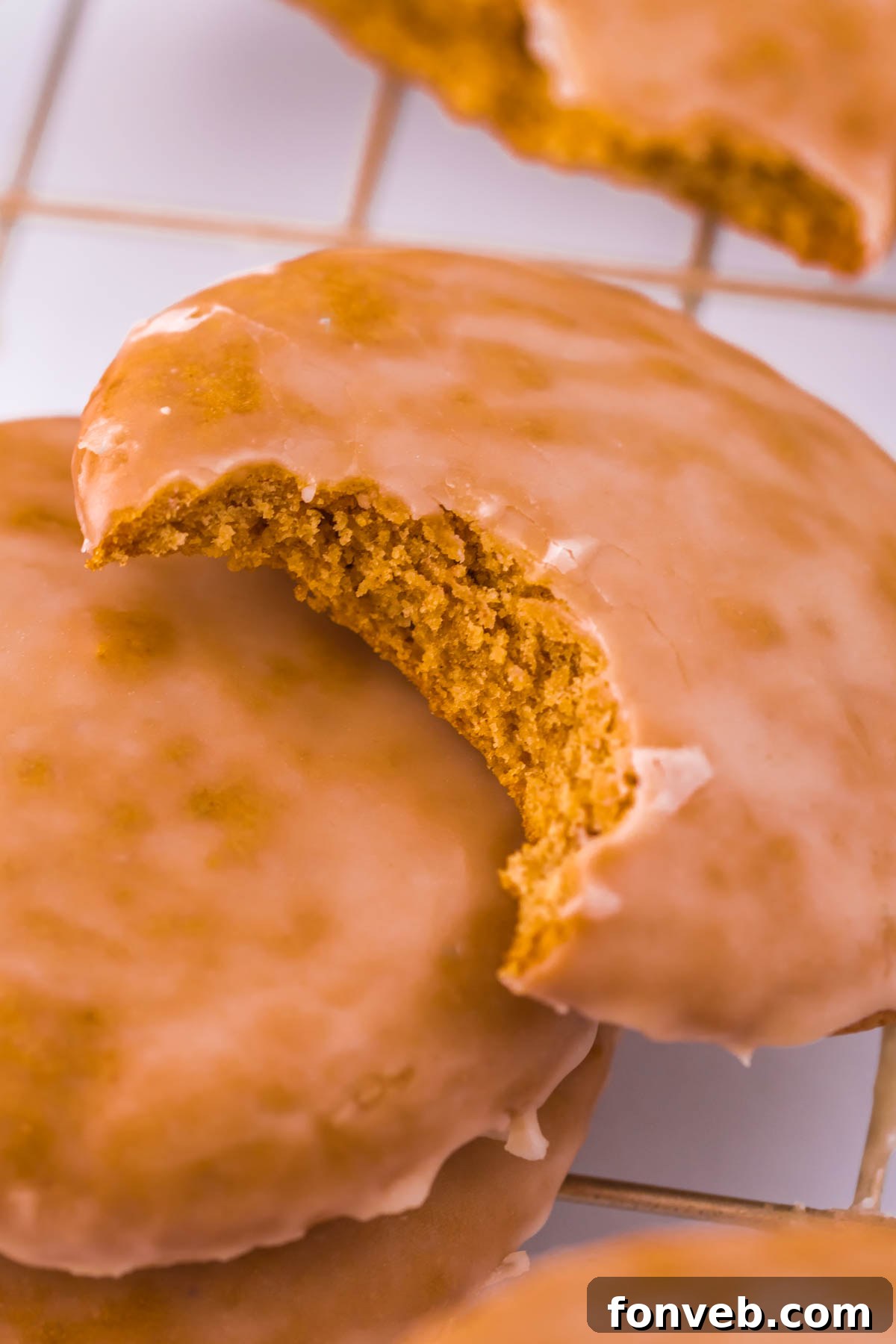 A perfectly glazed Lebkuchen gingerbread cookie with a bite taken out, resting on a rustic wooden table.