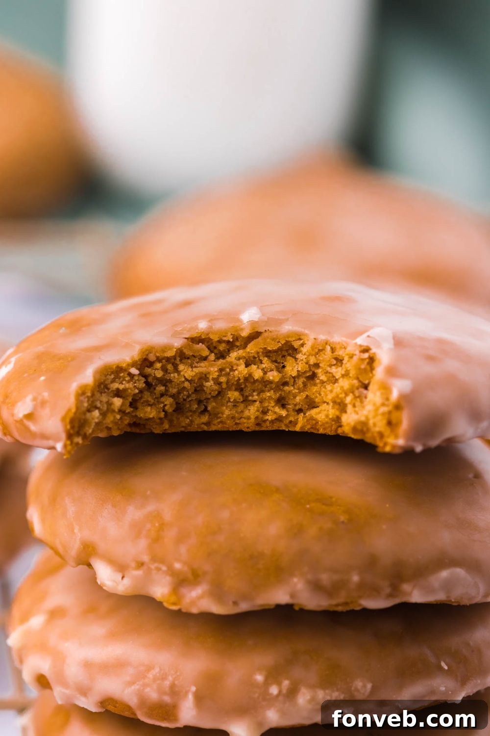 A stack of freshly baked cookies, with one showing a bite taken out, arranged on a cooling rack.