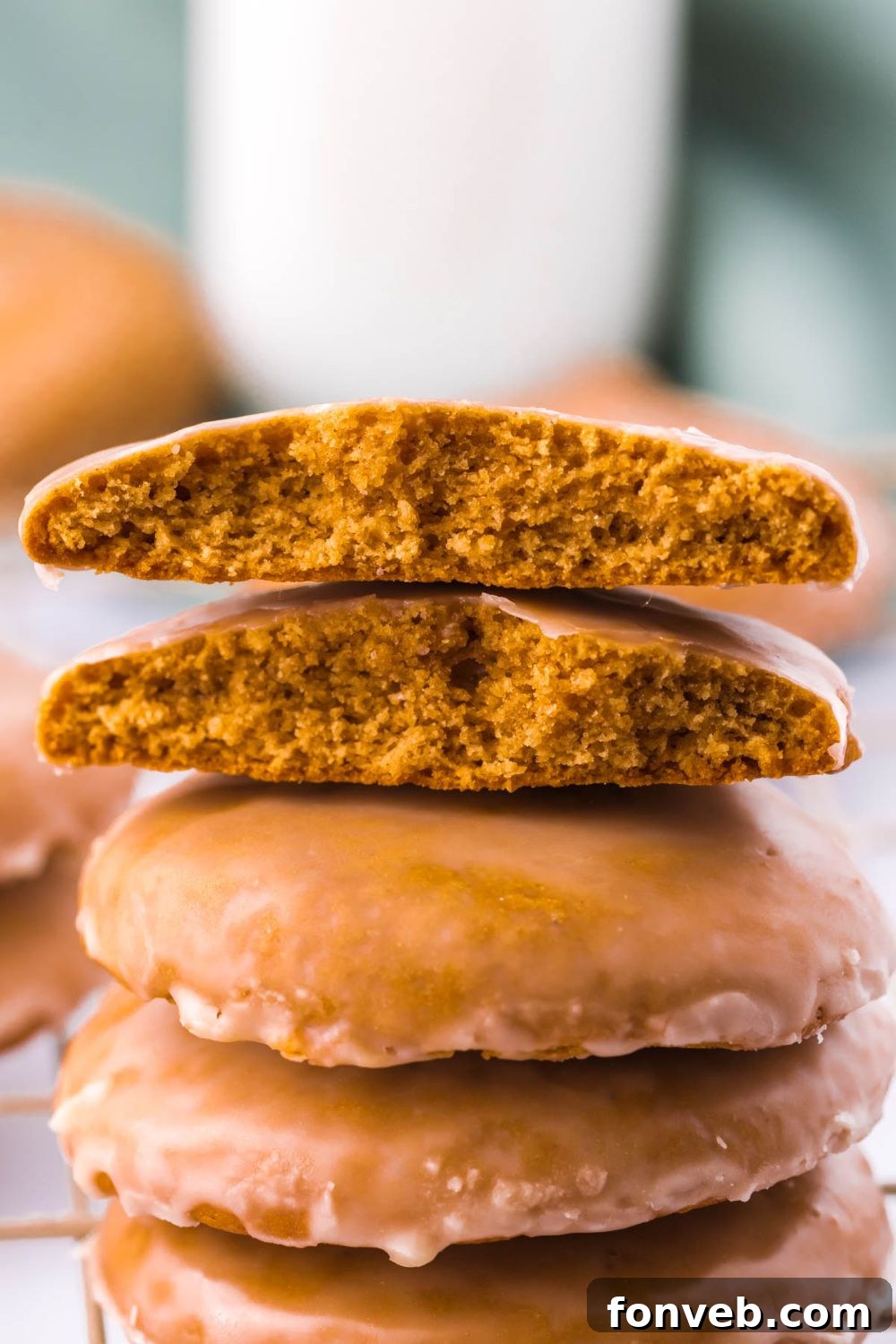 A stack of beautifully glazed Lebkuchen gingerbread cookies, with one broken in half on top to reveal its soft interior.
