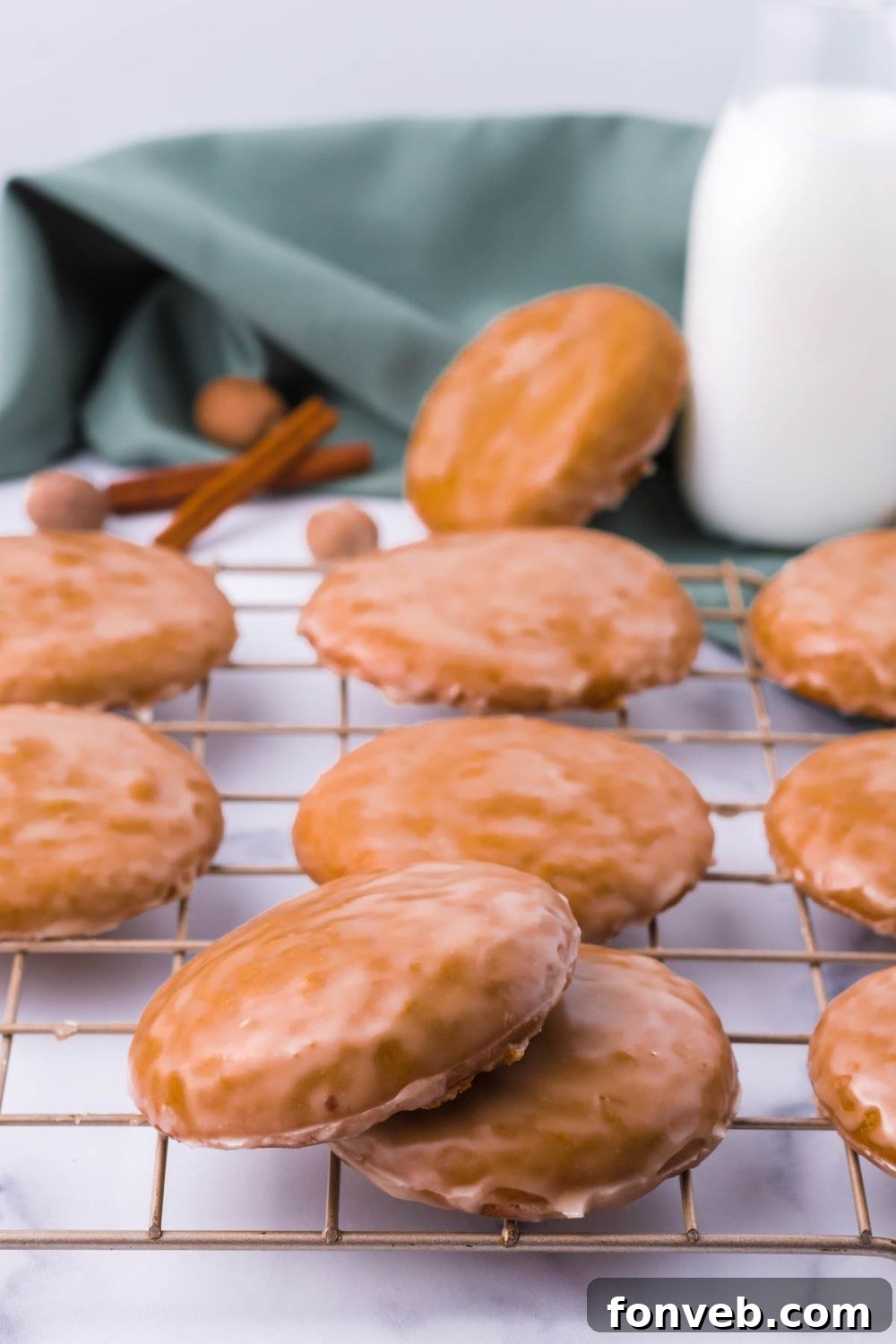 A cooling rack filled with freshly baked German cookies, with a bottle of milk elegantly placed behind it on a table.