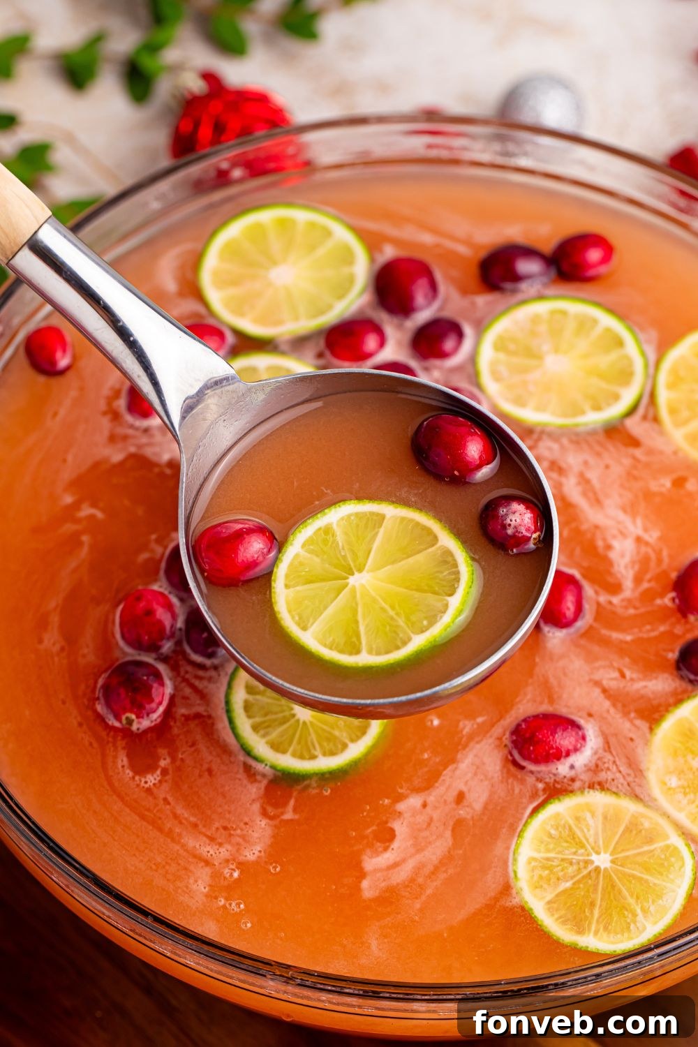 A ladle serving a frothy punch from a bowl, garnished with colorful fruit, highlighting the creamy texture.