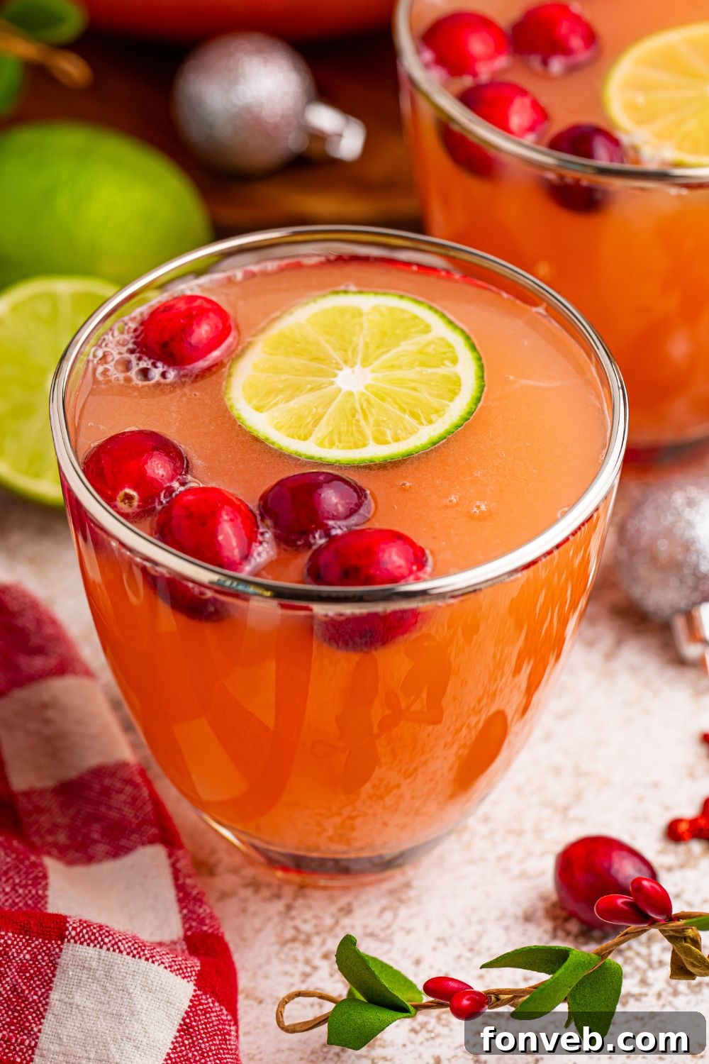 Close-up of a glass of Santa's Giggle Juice Punch, showing the layered colors and frothy top, set on a table.