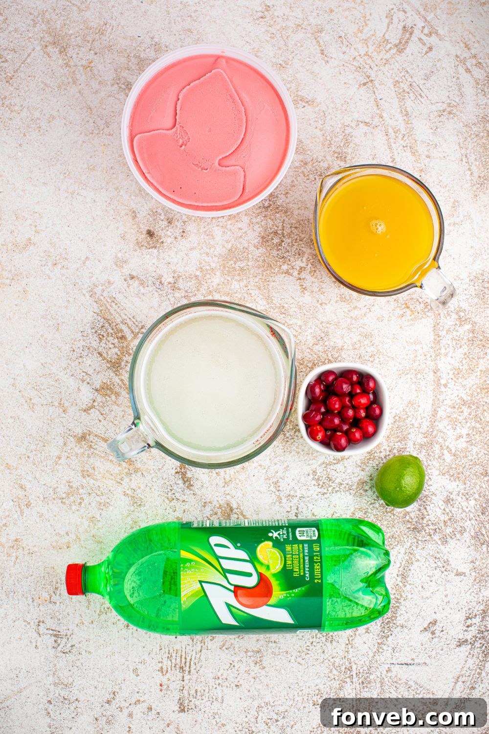 Assortment of ingredients for Santa's Giggle Juice Punch, including a bottle of limeade, 7UP, pineapple juice, and a container of sherbet, neatly arranged on a table.