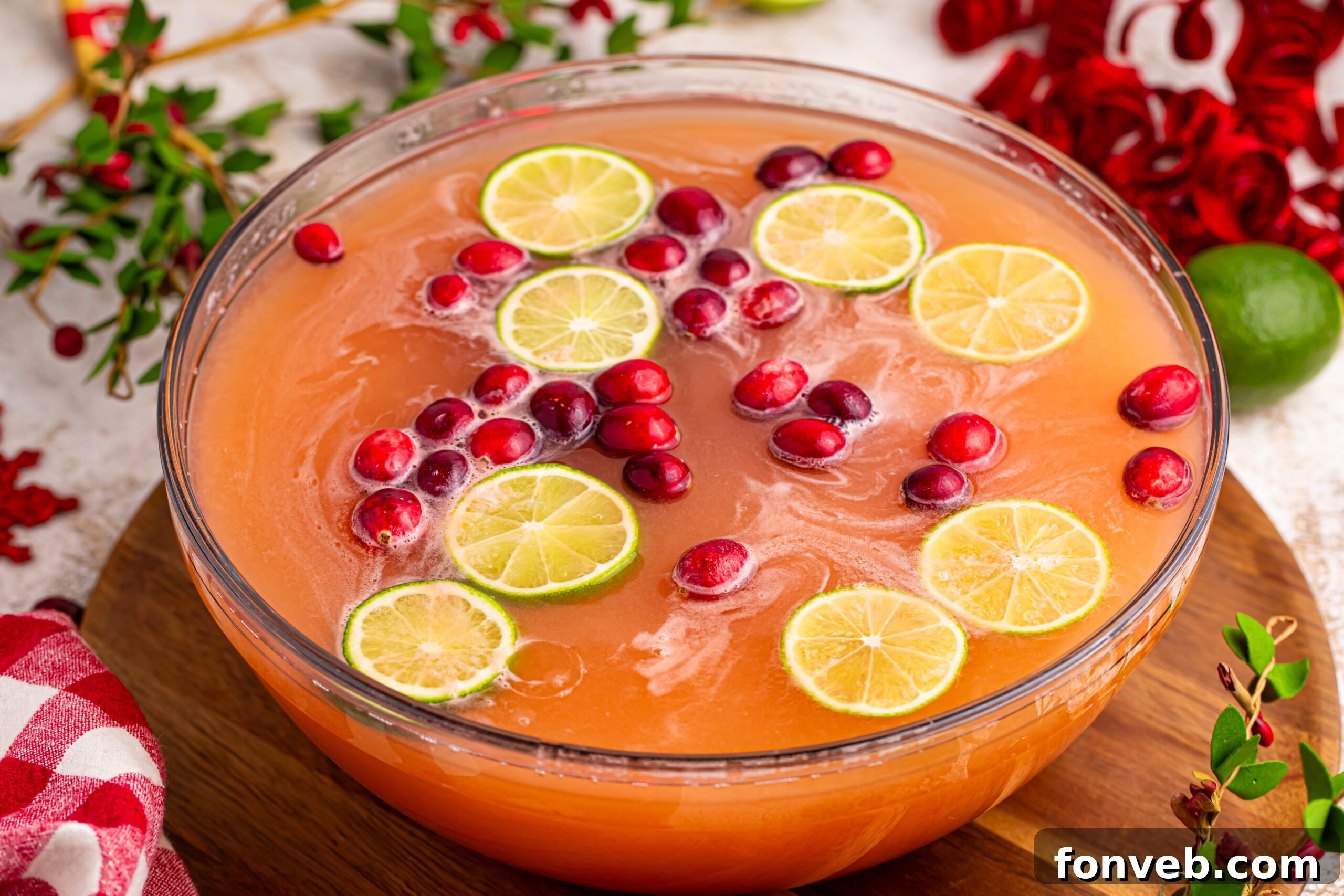 Santa's Giggle Juice Punch in a large punch bowl, garnished with fruit and a ladle, on a elegant wooden table, ready for serving.