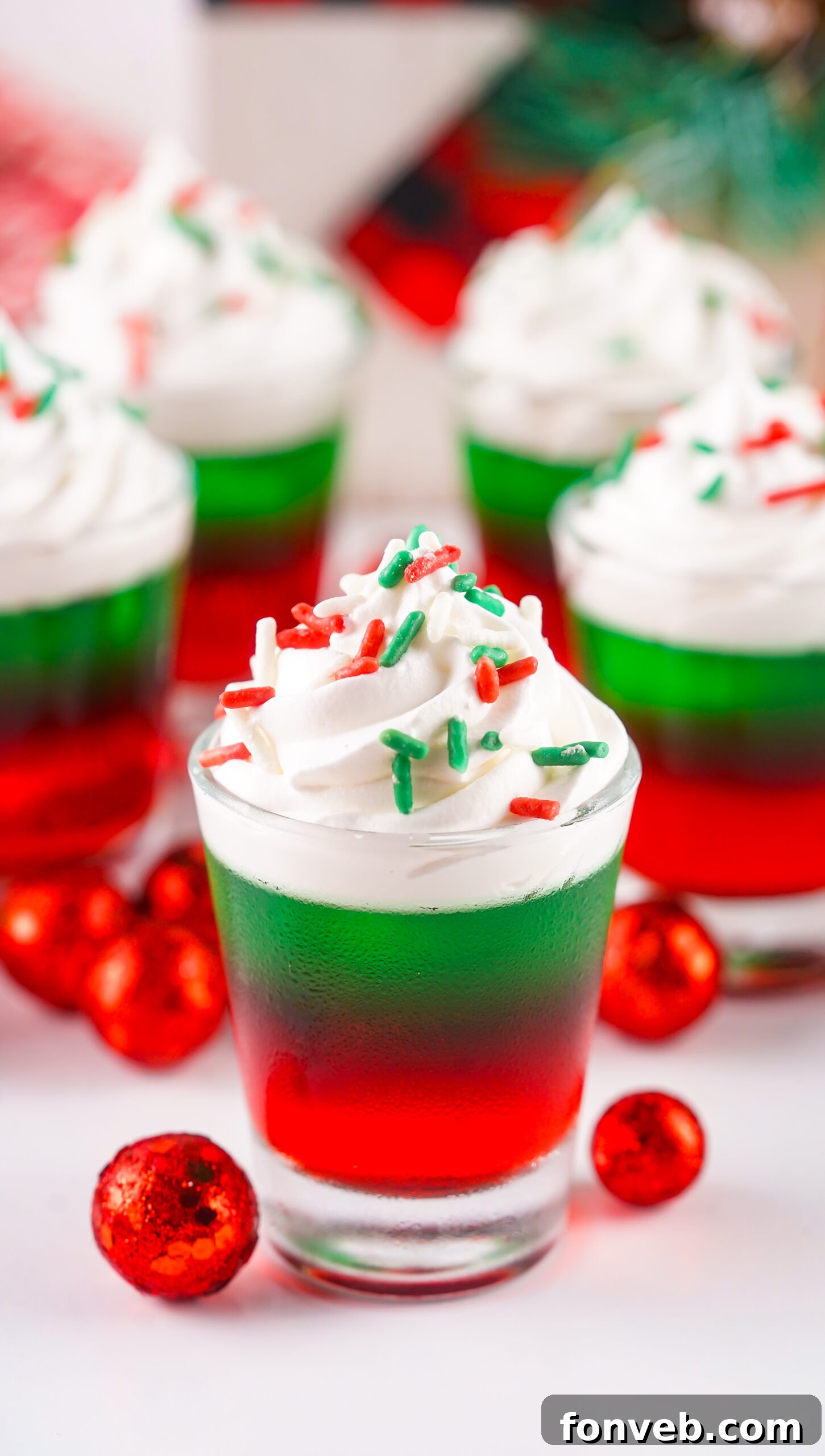 Yuletide Jiggle Shots 15 Christmas Jello Shots on a white able with red ornaments around them