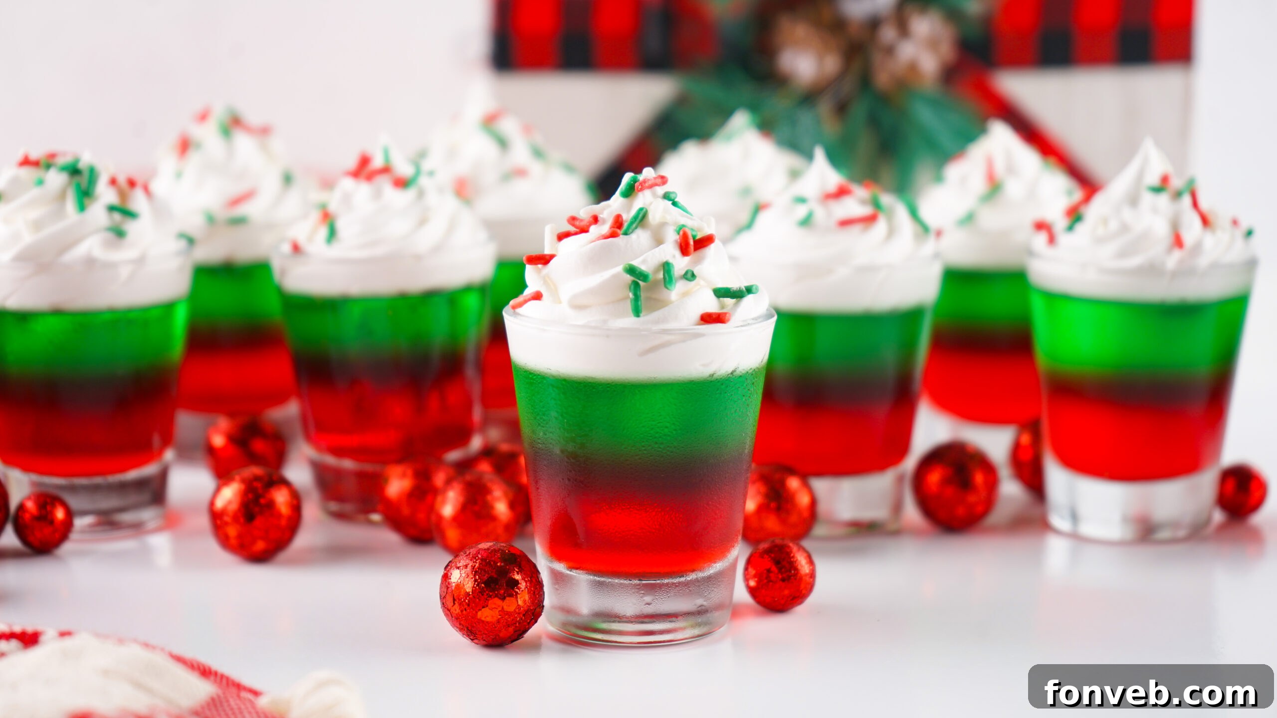 Yuletide Jiggle Shots 19 Christmas Jello Shots on a white table with red ornaments around them