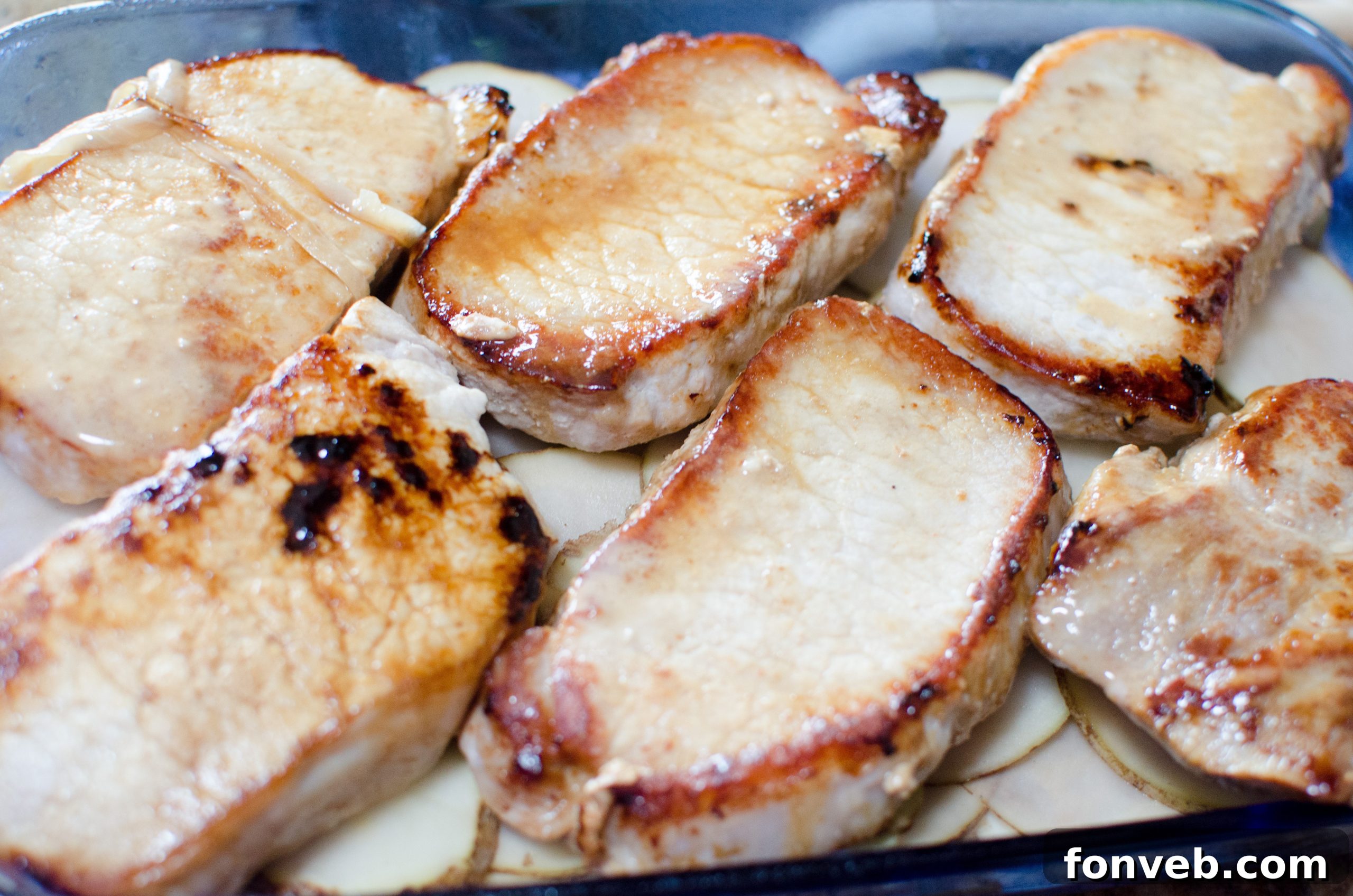 Golden brown pork chops resting on a plate after being seared, ready to be added to the casserole.