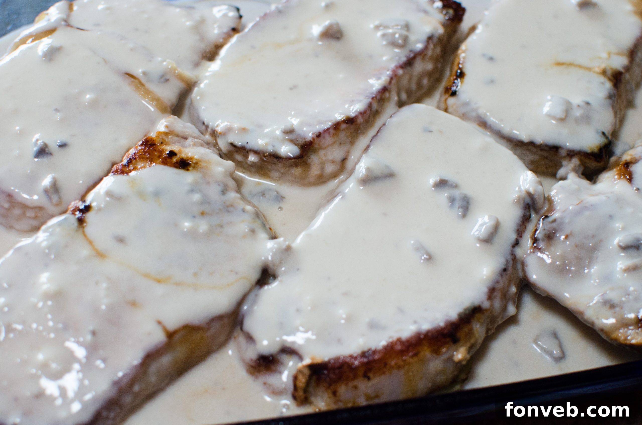 Cream of mushroom soup being stirred into sautéed onions, forming a rich and creamy base for the casserole.