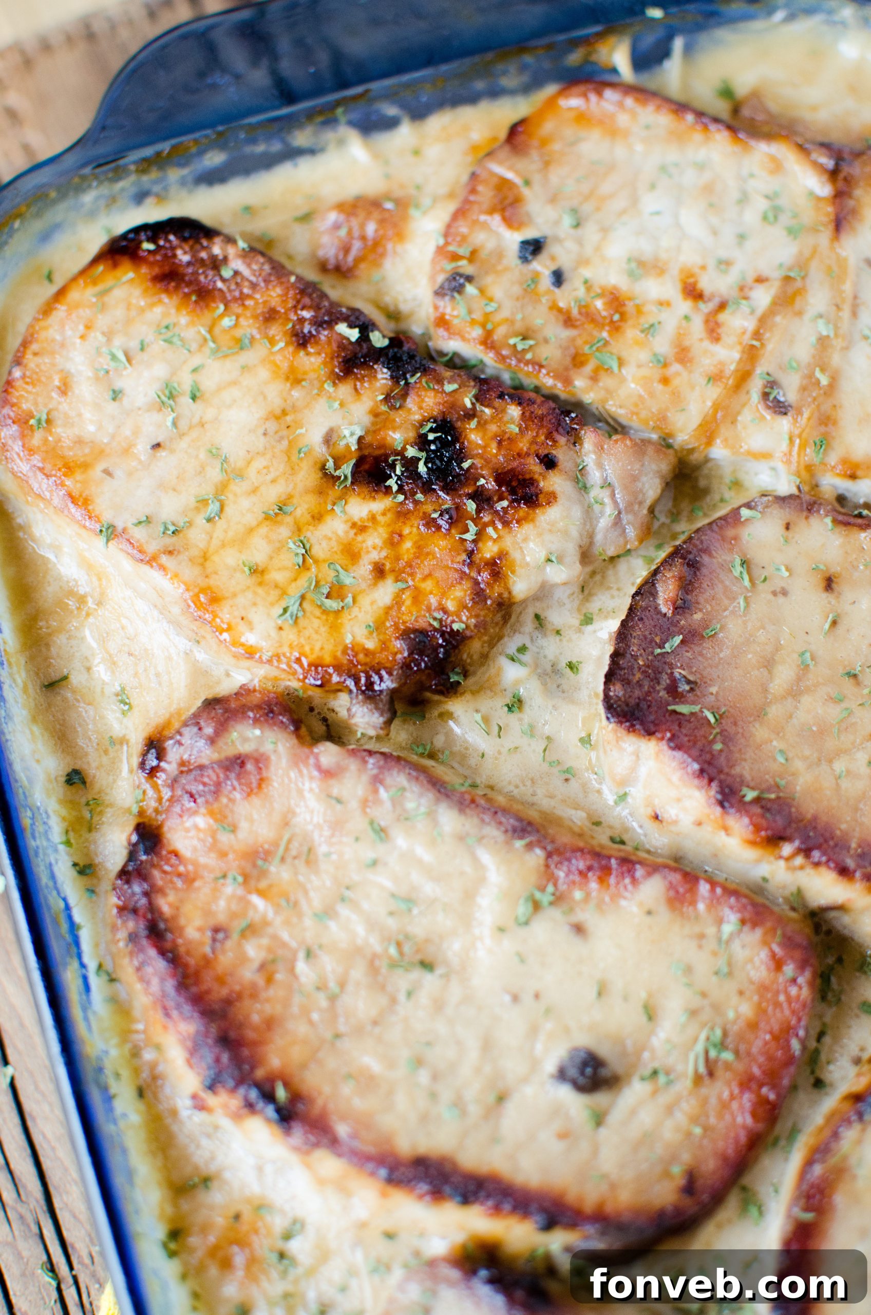The creamy sauce poured generously over the pork chops and potatoes in the baking dish, ready for baking.
