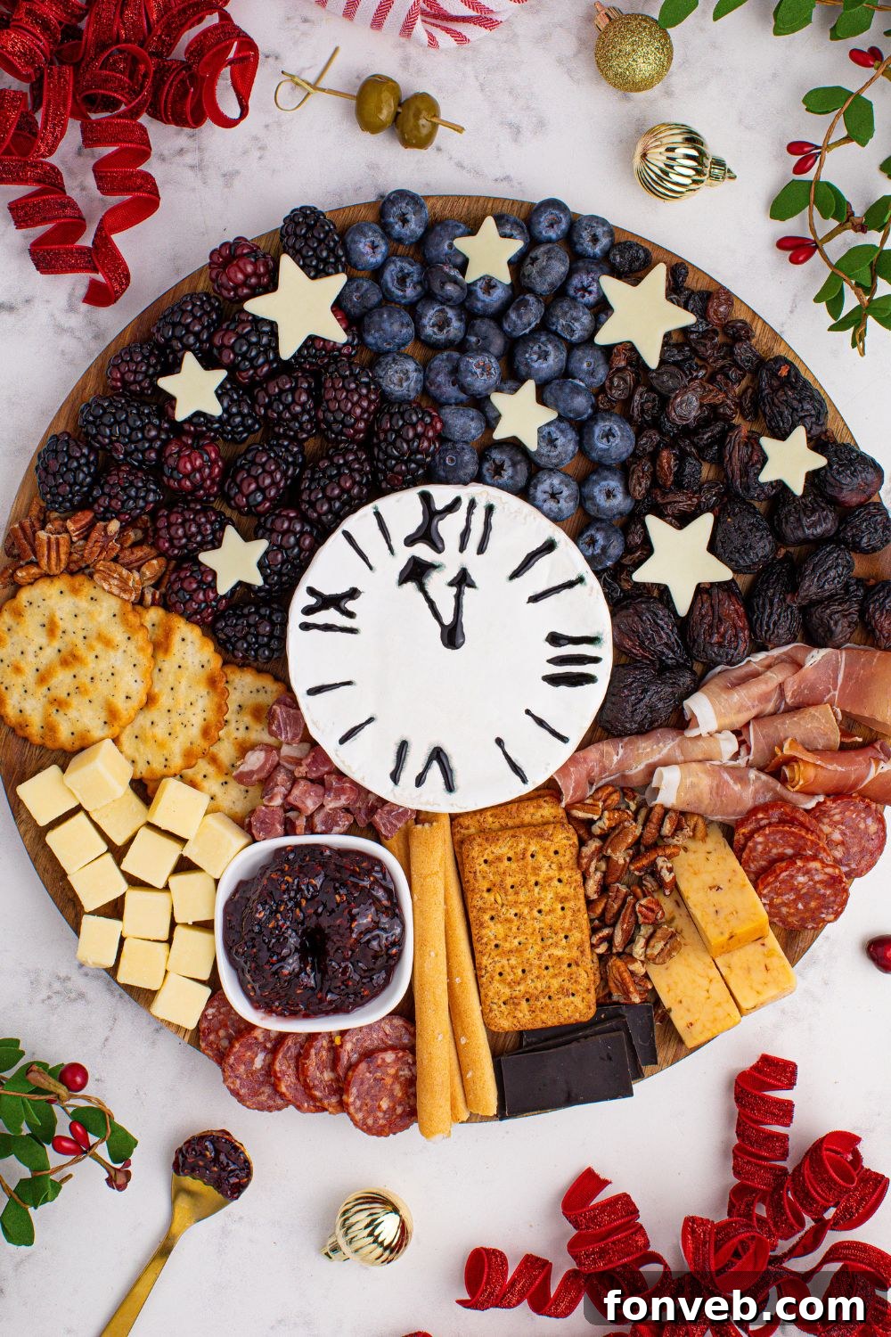 The New Year's Eve Charcuterie Board gracefully positioned on a table, surrounded by charming Christmas decor and scattered fresh fruits, creating a warm and inviting atmosphere.