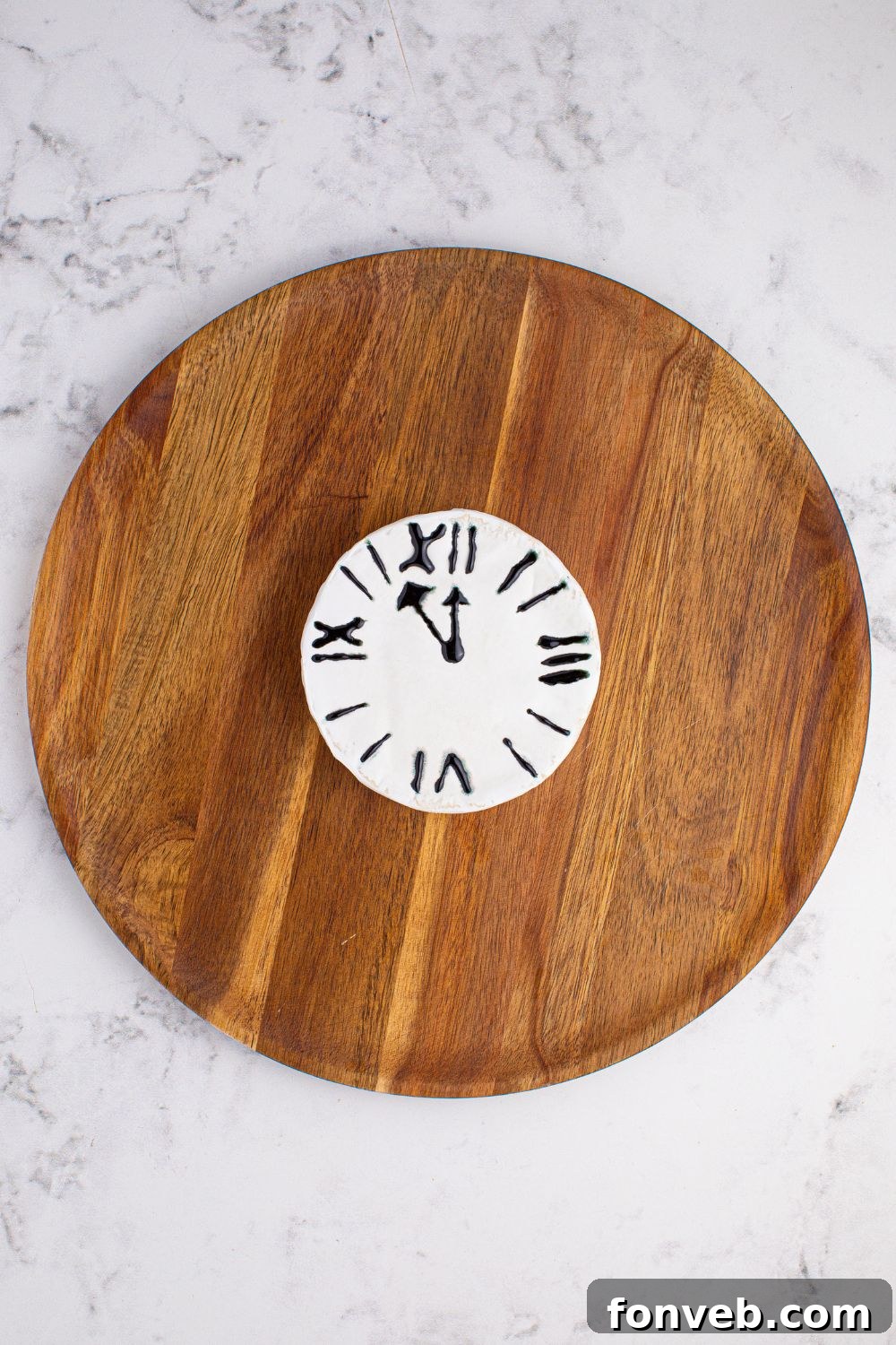 A New Year's Eve Charcuterie Board featuring a Brie cheese in the center, artfully decorated to resemble a clock face, surrounded by an assortment of delectable snacks.