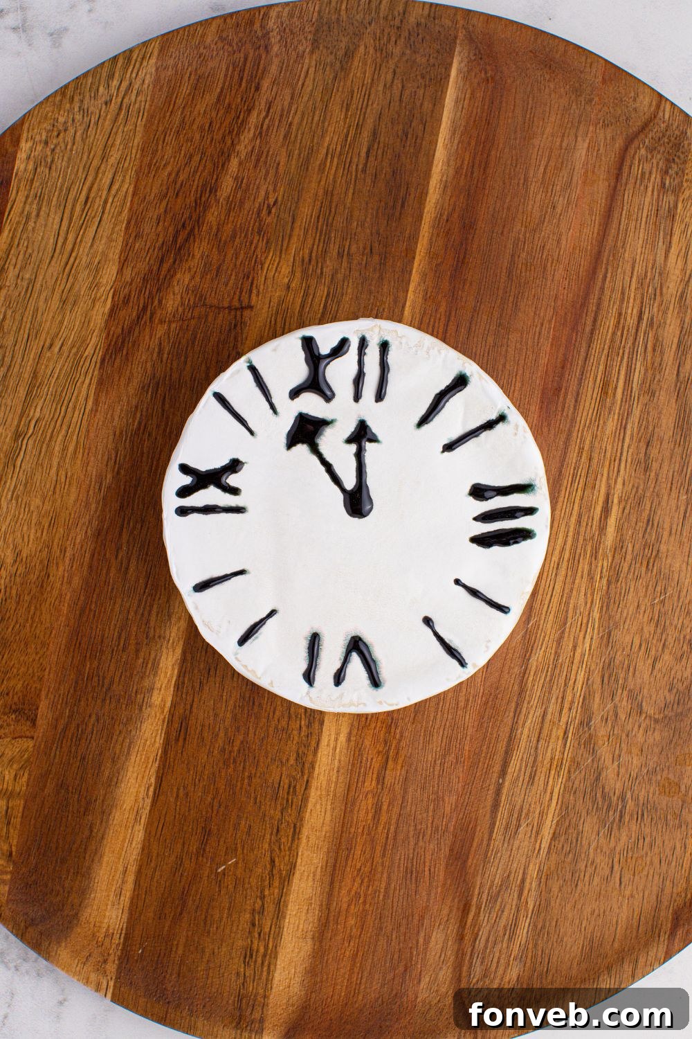 The initial stages of assembling a New Year's Eve Charcuterie Board, prominently featuring the Brie cheese with a clock face already drawn on it, ready for further arrangements.