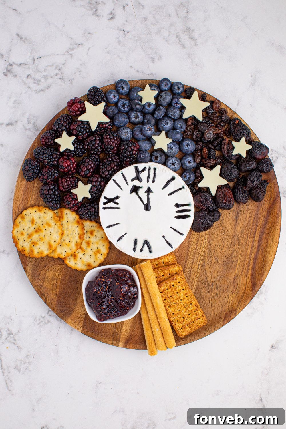A New Year's Eve Charcuterie Board in progress, with fruits and crackers elegantly spread on a serving tray, creating a vibrant and appealing display.