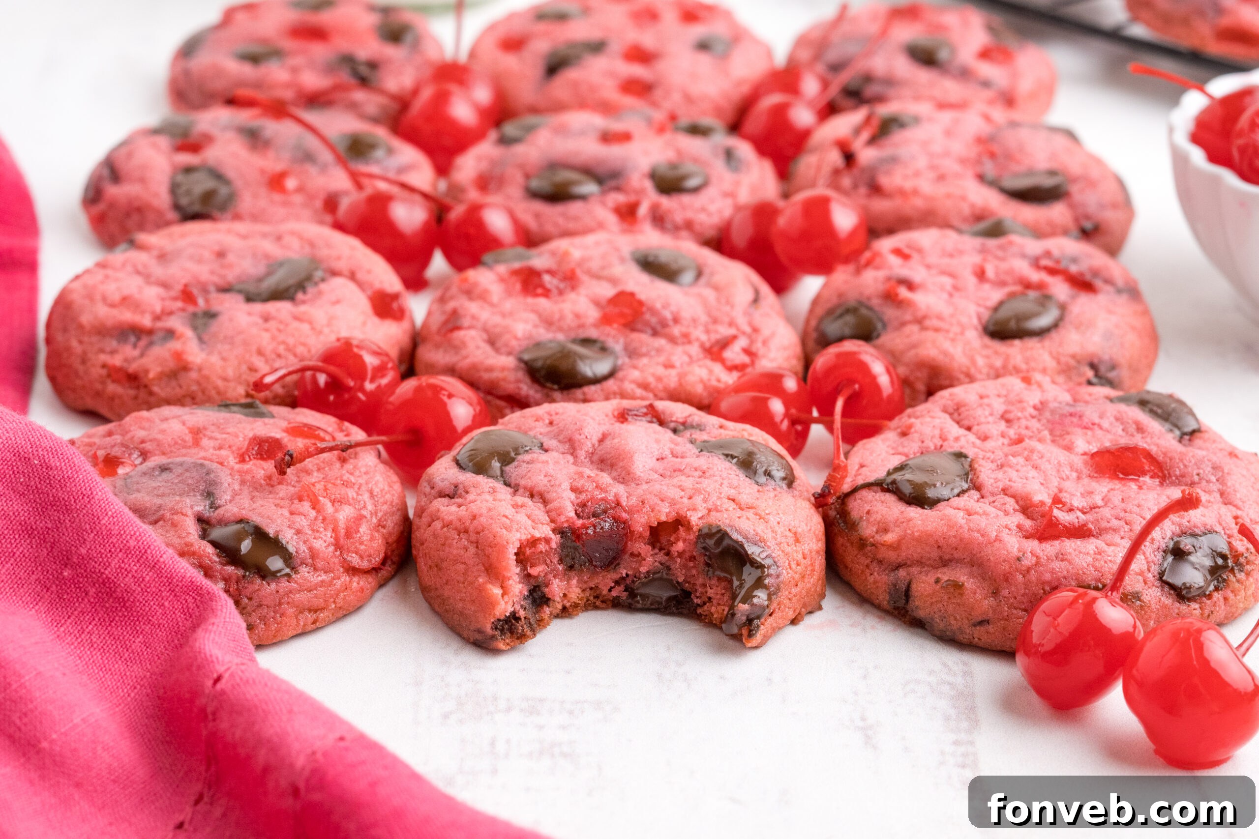 Cherry Chocolate Chip Cookies on a white table with a few cherries in front 