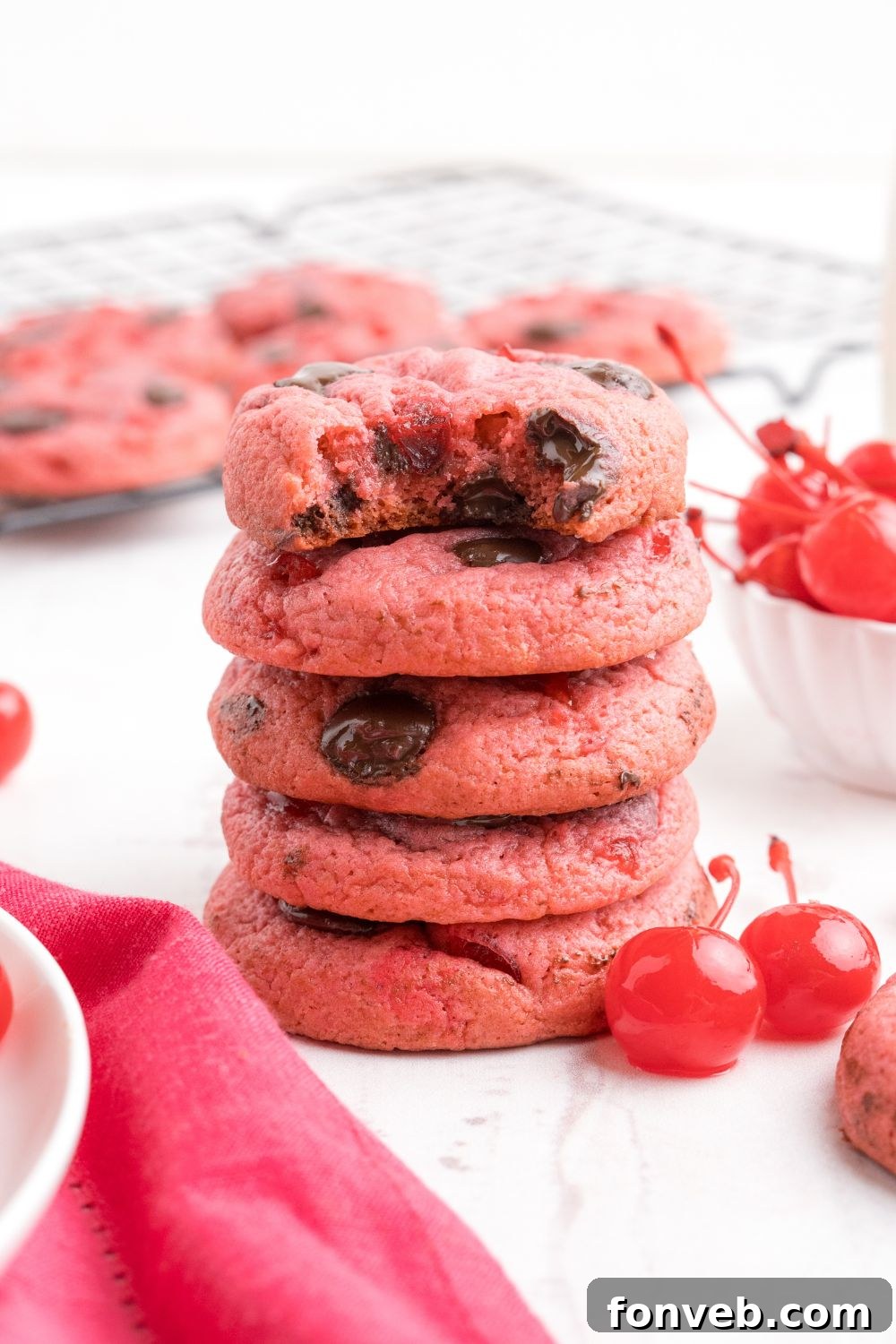Cherry Chocolate Chip Cookies stacked on table with one bite taken out of the cookie 