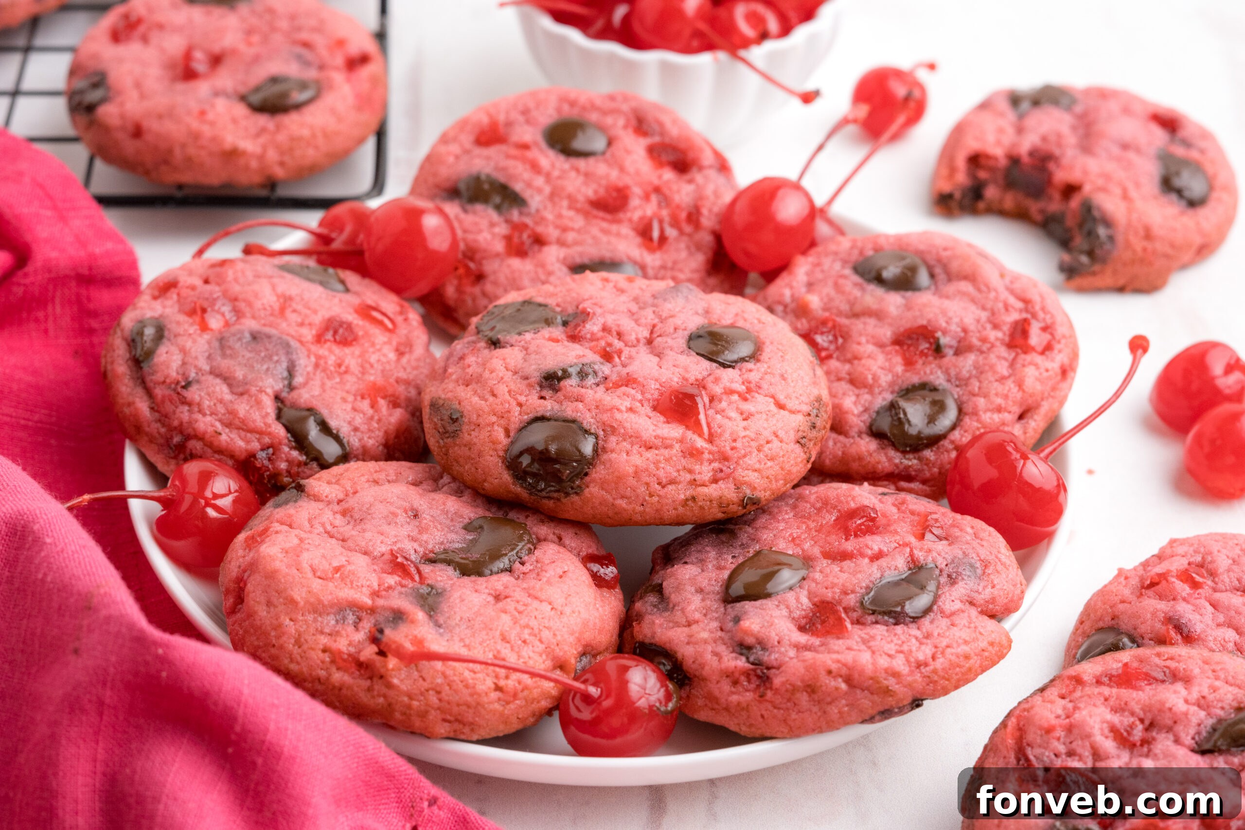 Cherry Chocolate Chip Cookies on a white plate with a few cherries all around them 
