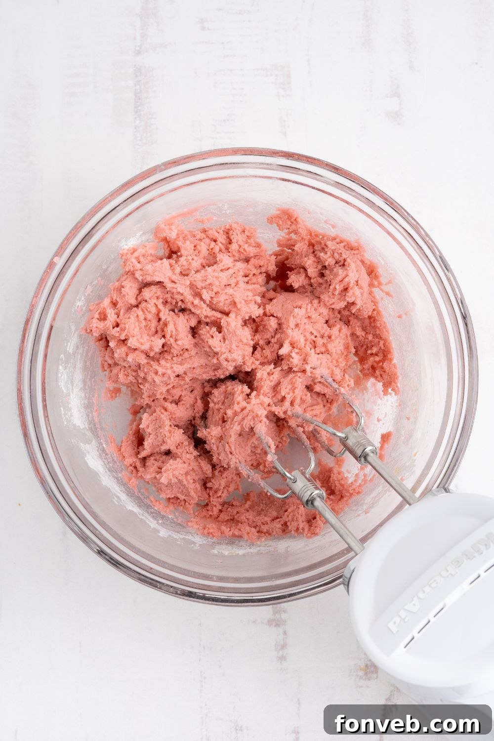 Cherry Chocolate Chip Cookie dough that is colored pink and being mixed with a hand mixer 