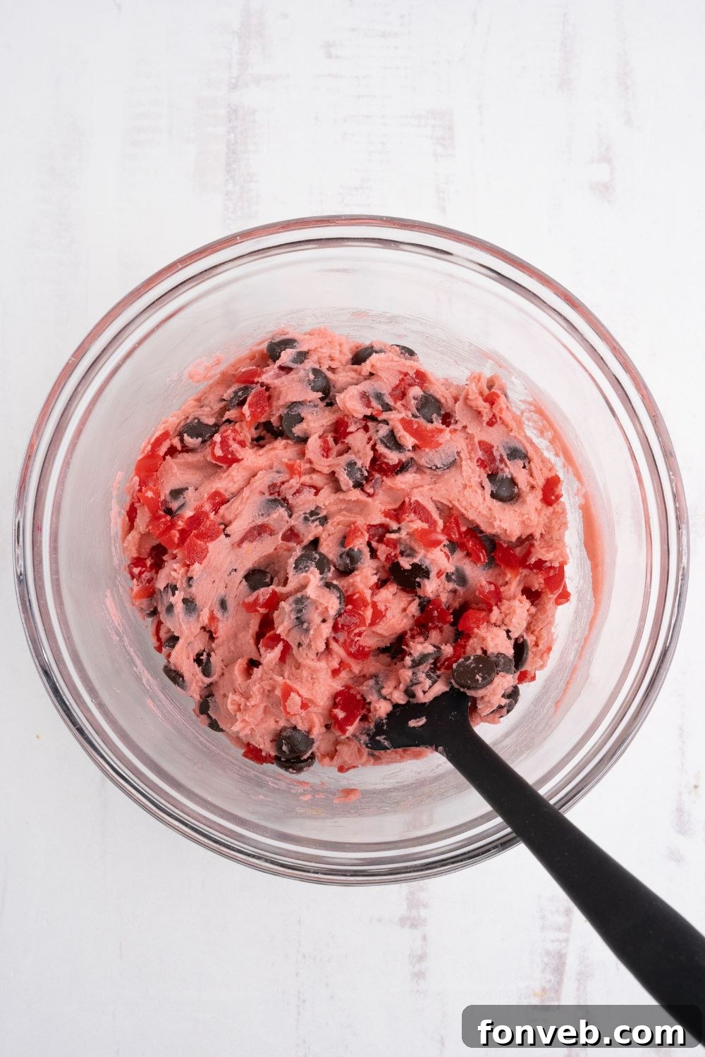 Cherry Chocolate Chip Cookie dough in a bowl with a spoon on the side 