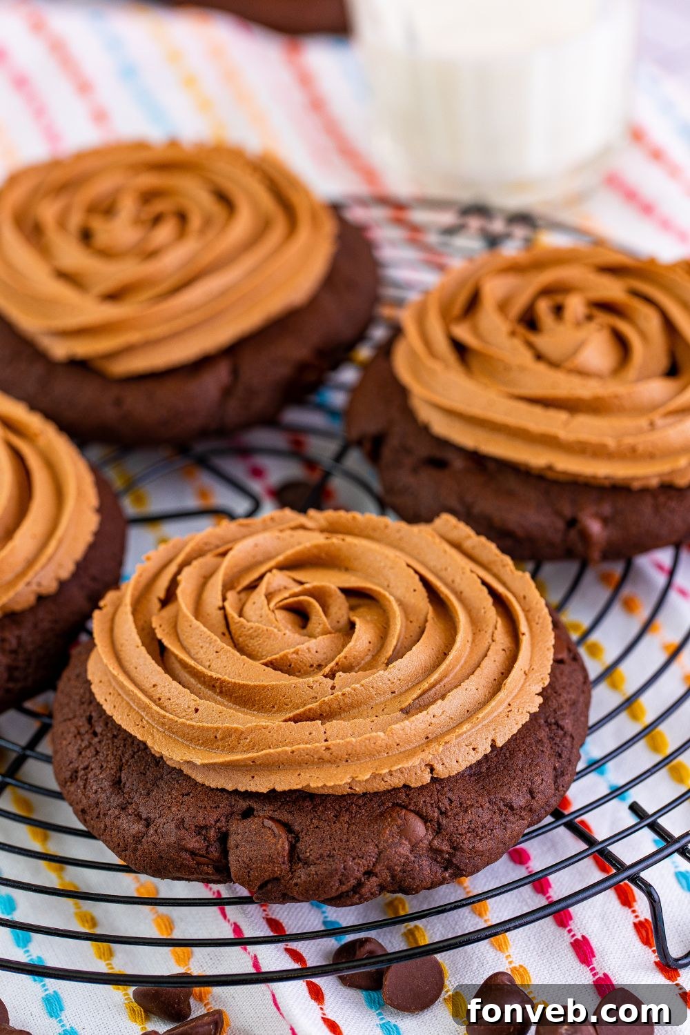 Chocolate Cake Cookies arranged on a wire rack with a glass of milk and scattered chocolate chips on the table