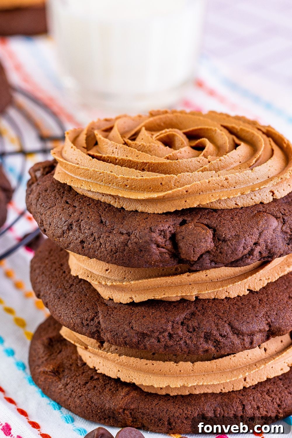 Several Chocolate Cake Cookies, beautifully frosted, stacked neatly on a wooden table