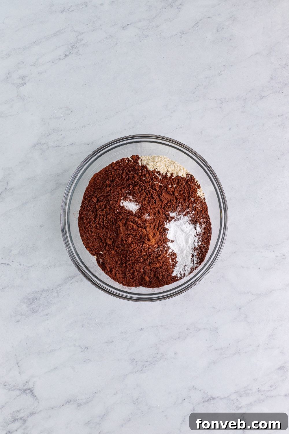 Dry ingredients, including flour and cocoa powder, in a clear glass bowl, ready to be mixed for Chocolate Cake Cookies