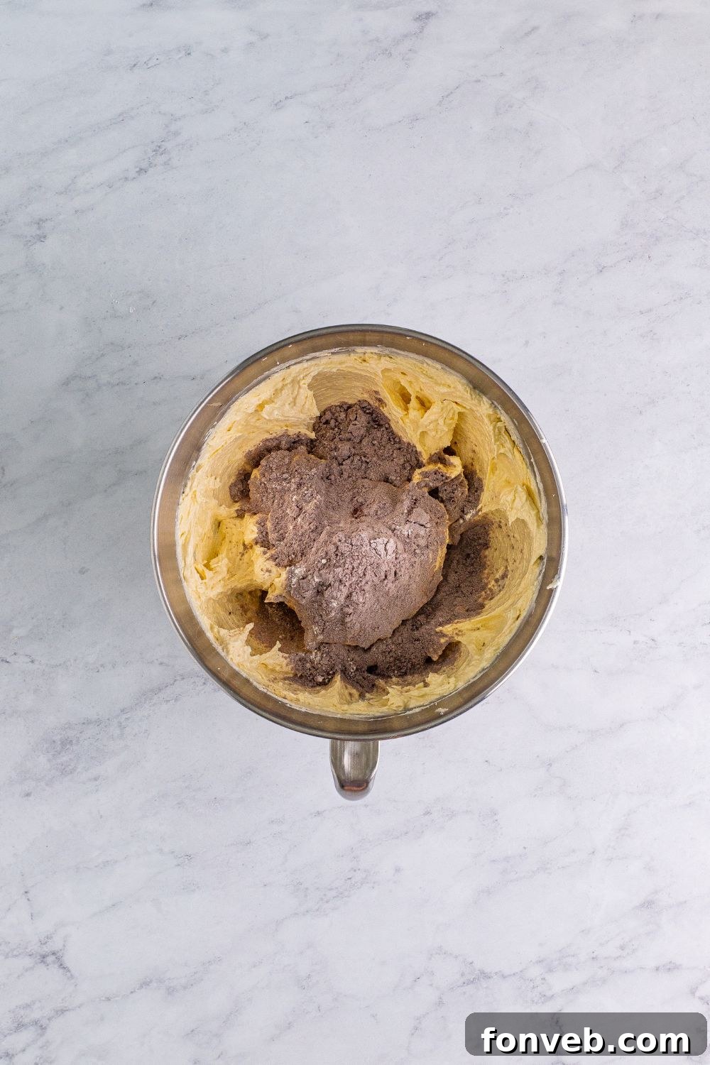 Dry ingredients being gradually added to the creamed butter mixture in a stand mixer, forming the dough for Chocolate Cake Cookies