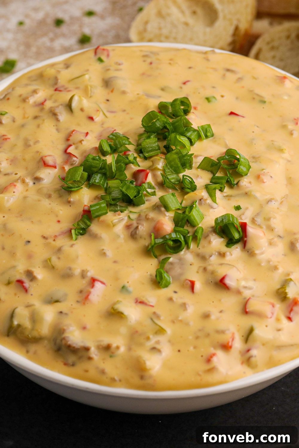 Crock Pot Philly Cheesesteak Dip in a glass bowl with green garnish on top sitting on table