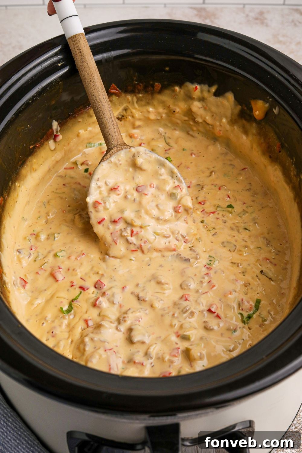 Crock Pot Philly Cheesesteak Dip in a slow cooker with a wooden spoon in the crockpot