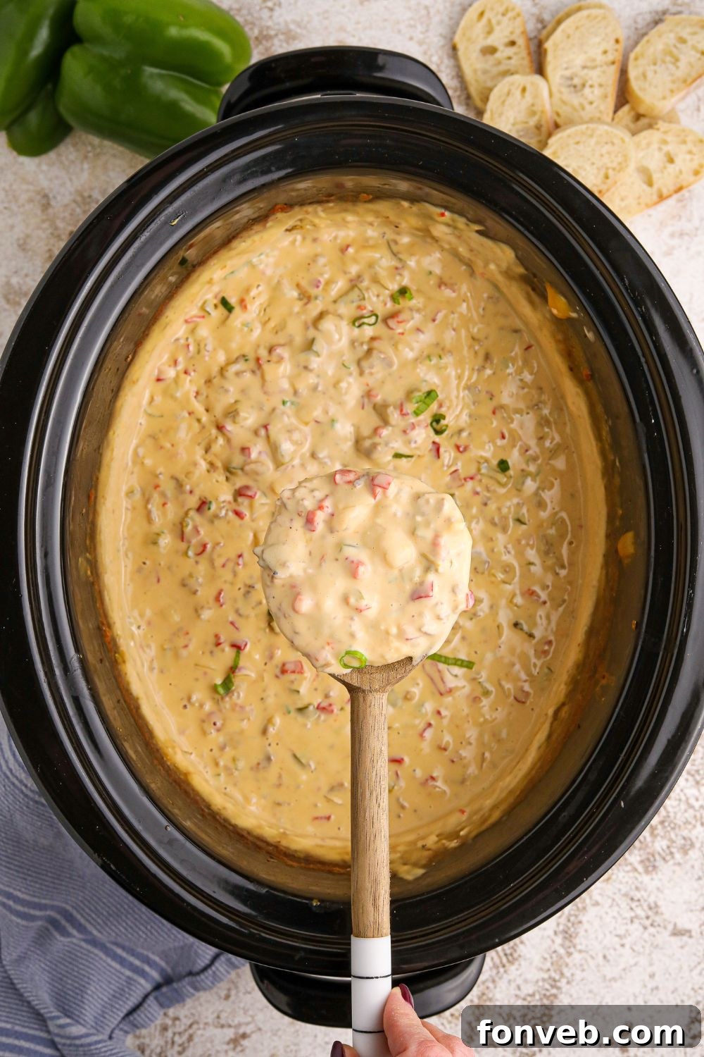 Crock Pot Philly Cheesesteak Dip in a slow cooker with a spoon full of dip over the crockpot