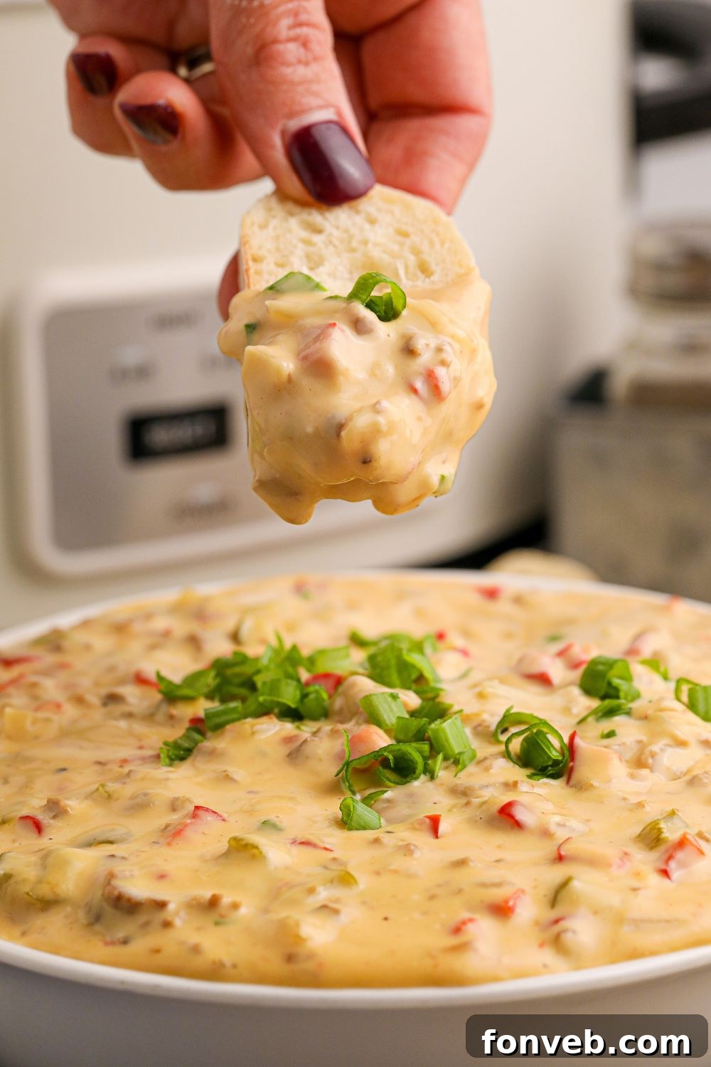 Crock Pot Philly Cheesesteak Dip in a bowl with a sliced bread dipped in the cheese sauce