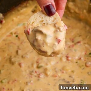 Crock Pot Philly Cheesesteak Dip on a piece of bread in hand over the crockpot full of dip