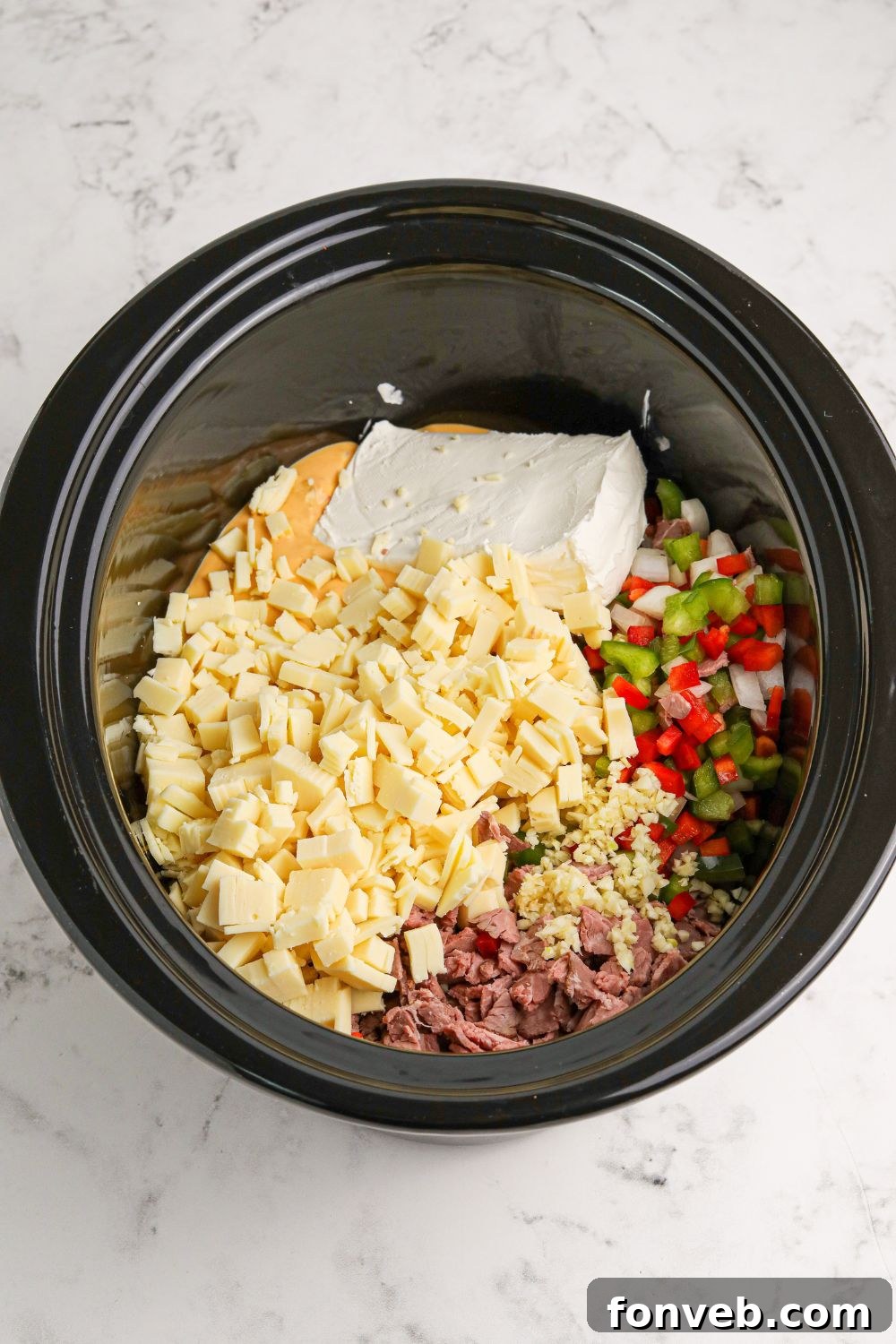 Crock Pot Philly Cheesesteak Dip ingredients in the slow cooker above the pan