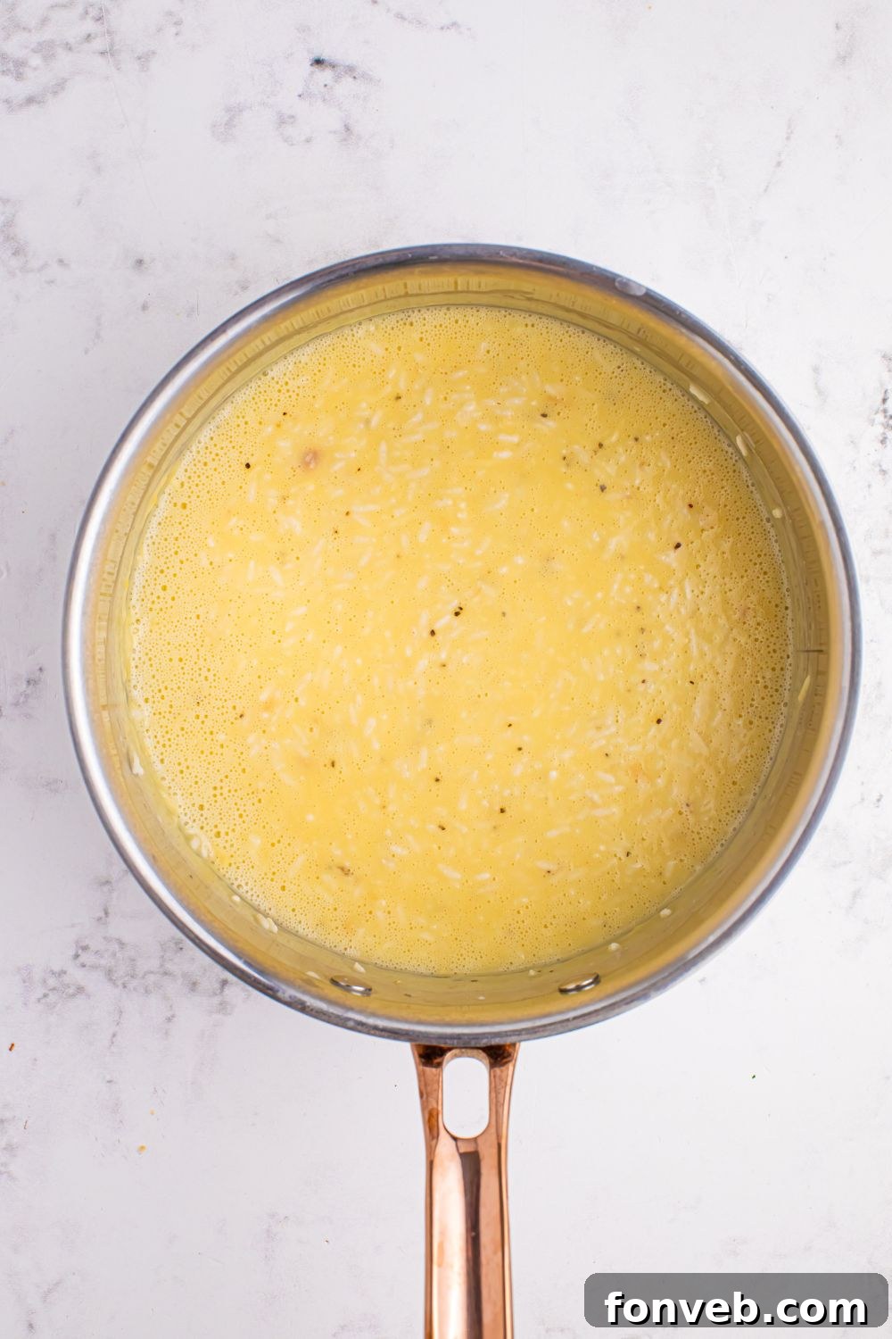 The creamy soup and broth mixture in a saucepan.